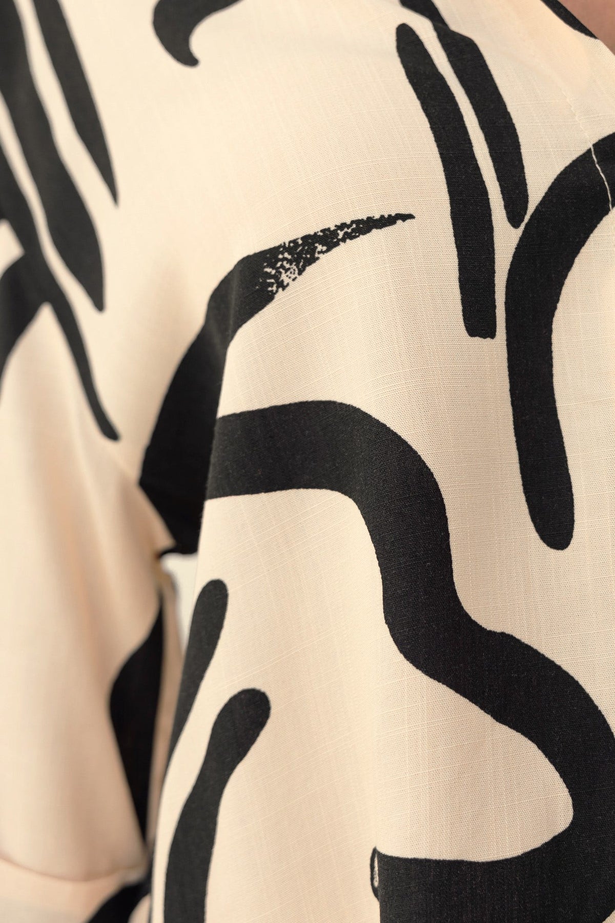 Close-up of abstract print fabric, showcasing black patterns on a light background, ideal for a stylish shirt.