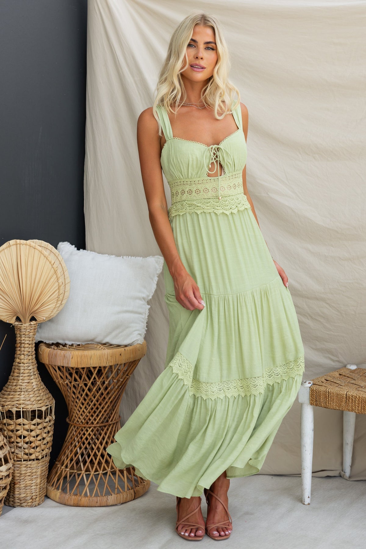 Flaria Maxi Dress in light green with tie detail and lace waist, styled in a bohemian setting.