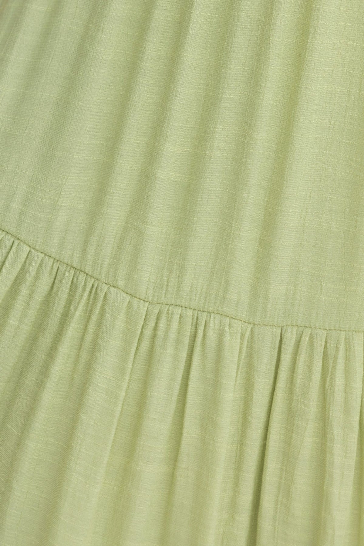 Close-up view of light green fabric featuring soft pleats, ideal for a stylish Flaria Maxi Dress.