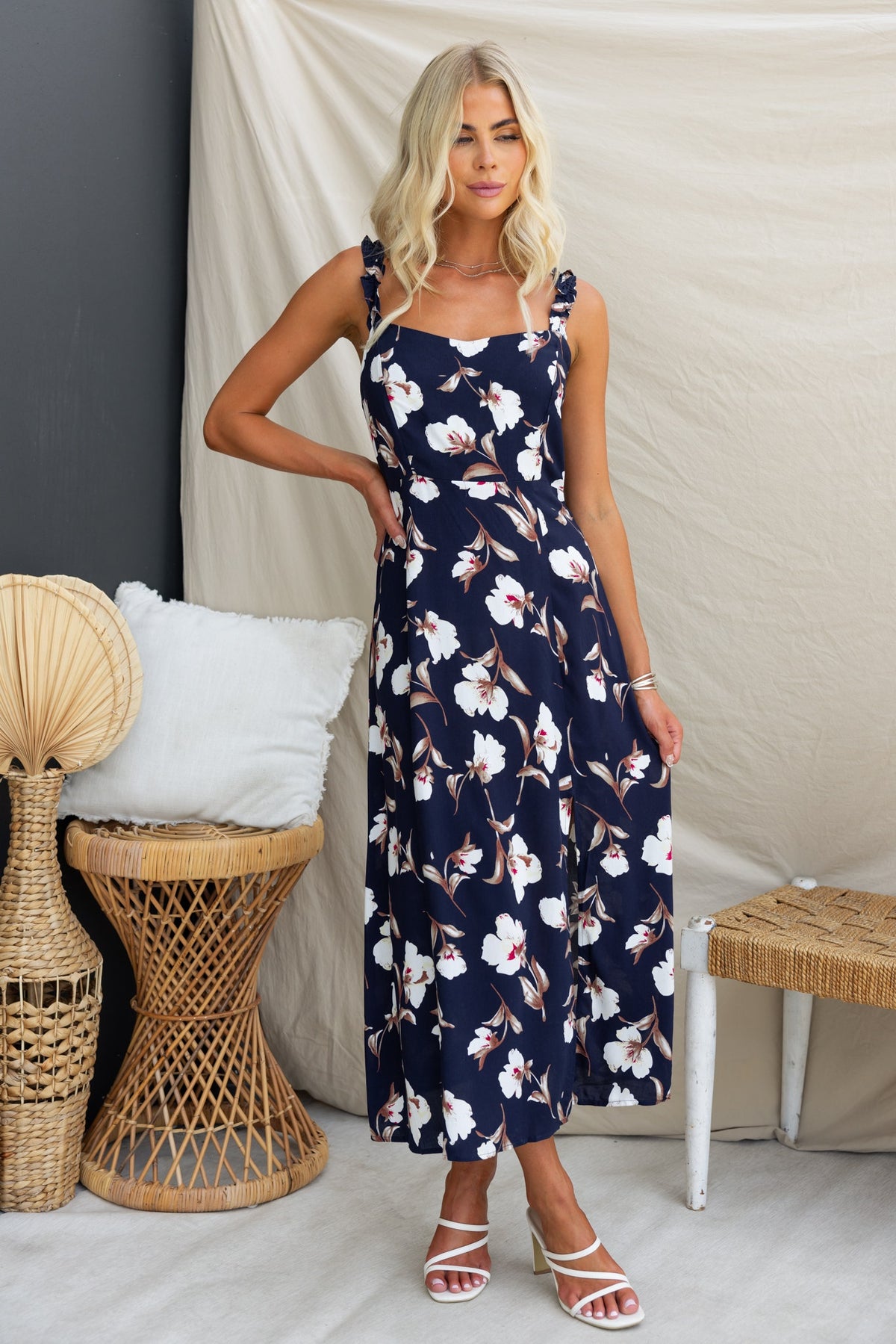 Model wearing a navy floral midi dress with adjustable straps and front split, showcasing a stylish summer look.