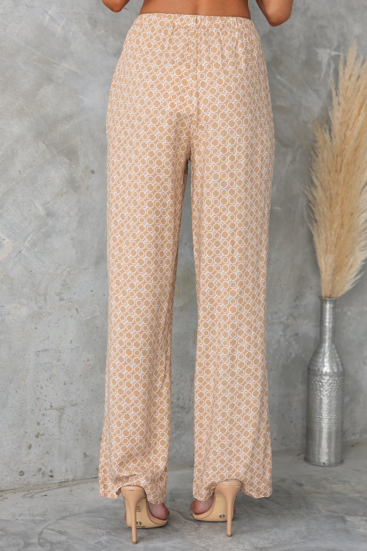 Back view of Okar Pants with abstract print, mid-high waist, elastic waistband, and light fabric.