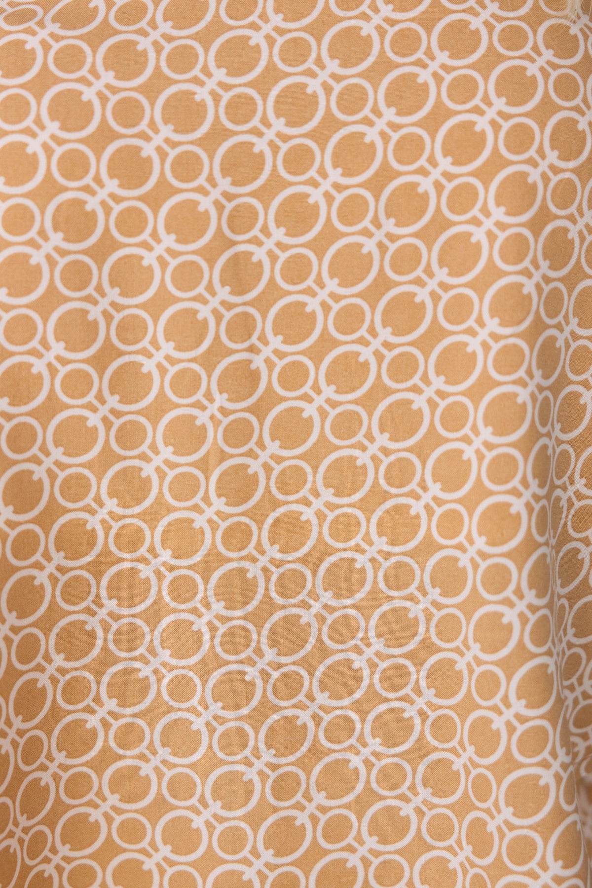 Close-up of abstract print fabric in orange and white, featuring a repeating circular pattern, ideal for stylish Okar Pants.