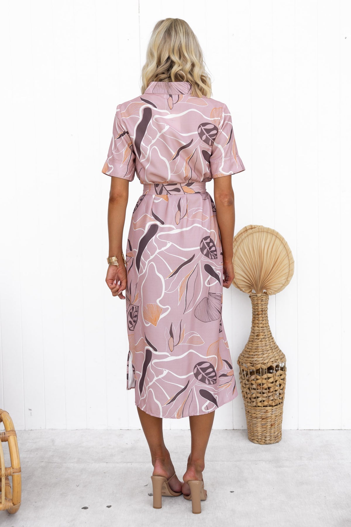 Back view of the Jubell Midi Dress featuring floral pattern, short sleeves, and a waist tie, styled with a decorative basket.
