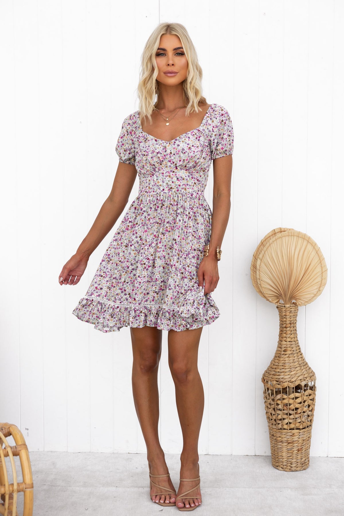 Cyan floral dress with elastic sleeves and side zip, styled on model standing against white background.