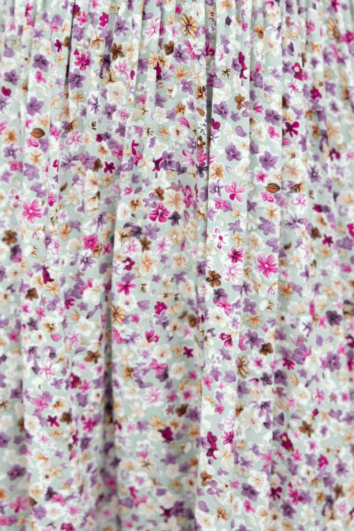 Close-up of floral fabric featuring purple, pink, and white flowers, ideal for a chic cyan dress.