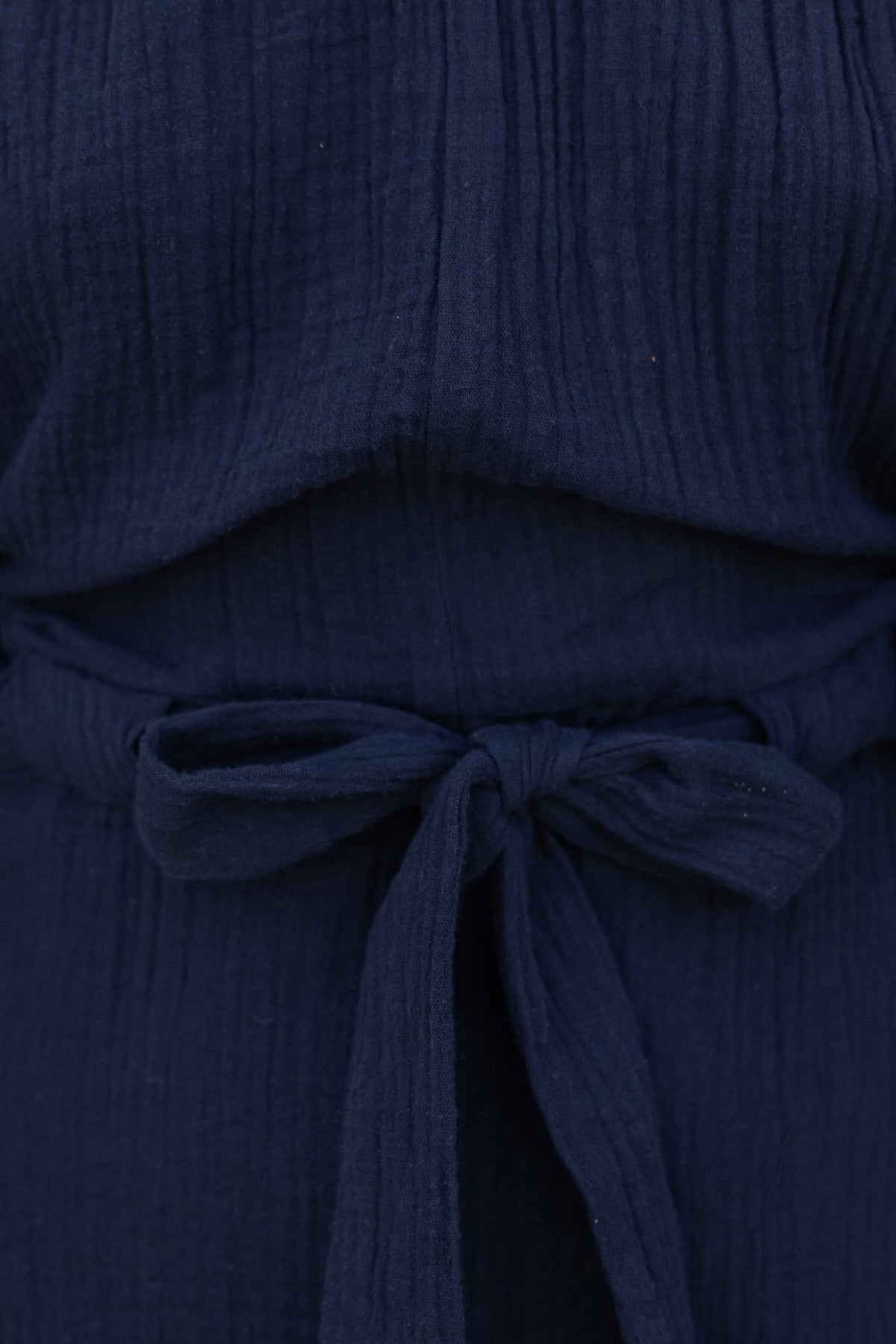 Close-up of the waistband tie detail of the Mykel Navy Dress, showcasing textured fabric and off-shoulder design.