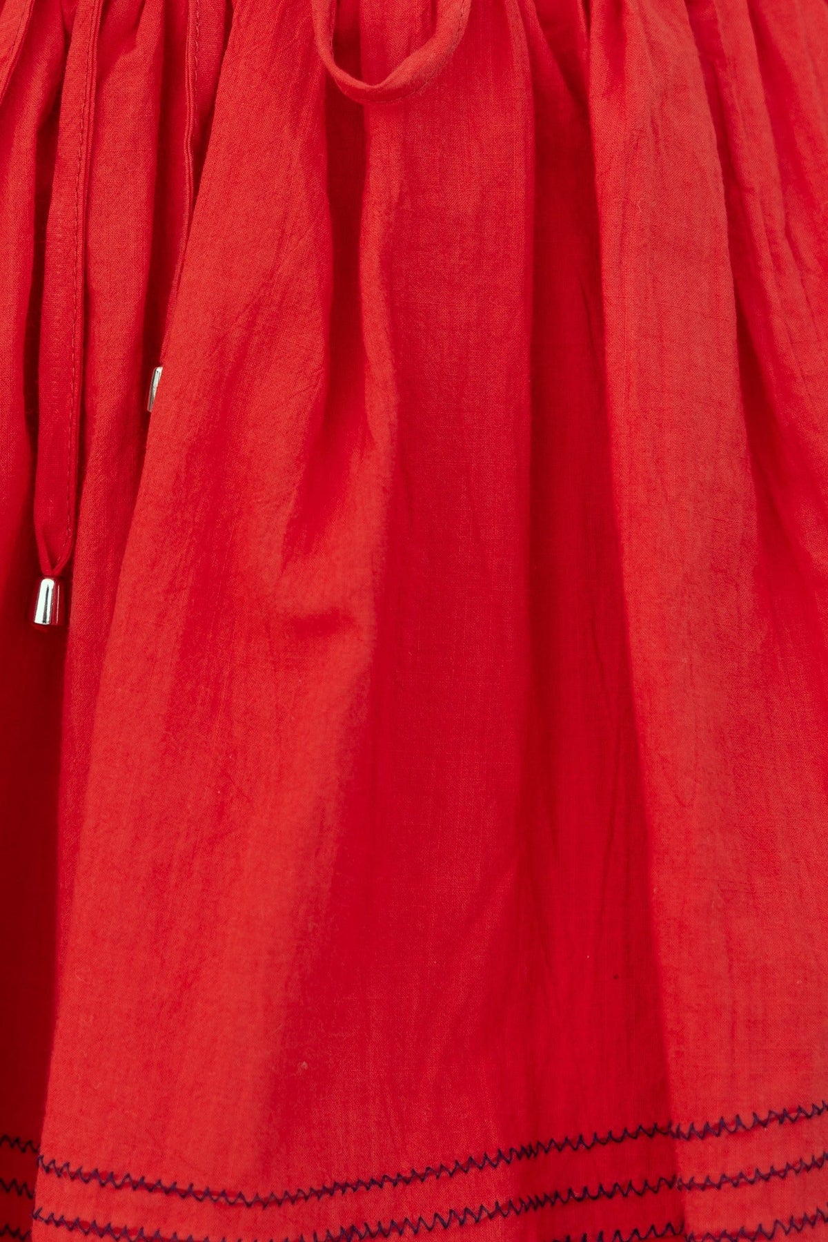 Close-up of red fabric with elastic waistband and drawstring detail for stylish shorts.