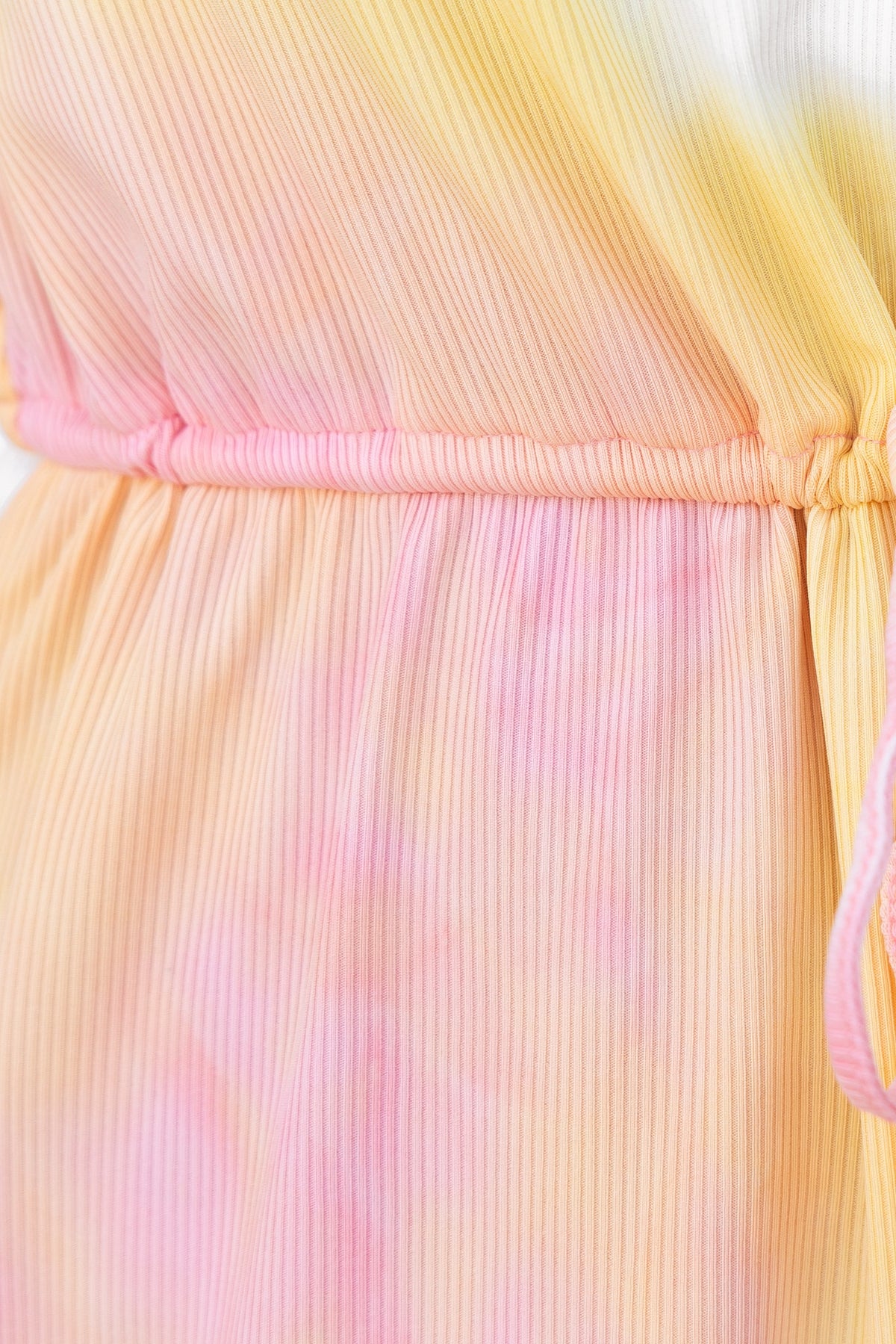 Close-up of the ribbed fabric and elastic waistband of the Hakuna Playsuit in pastel gradient colors.
