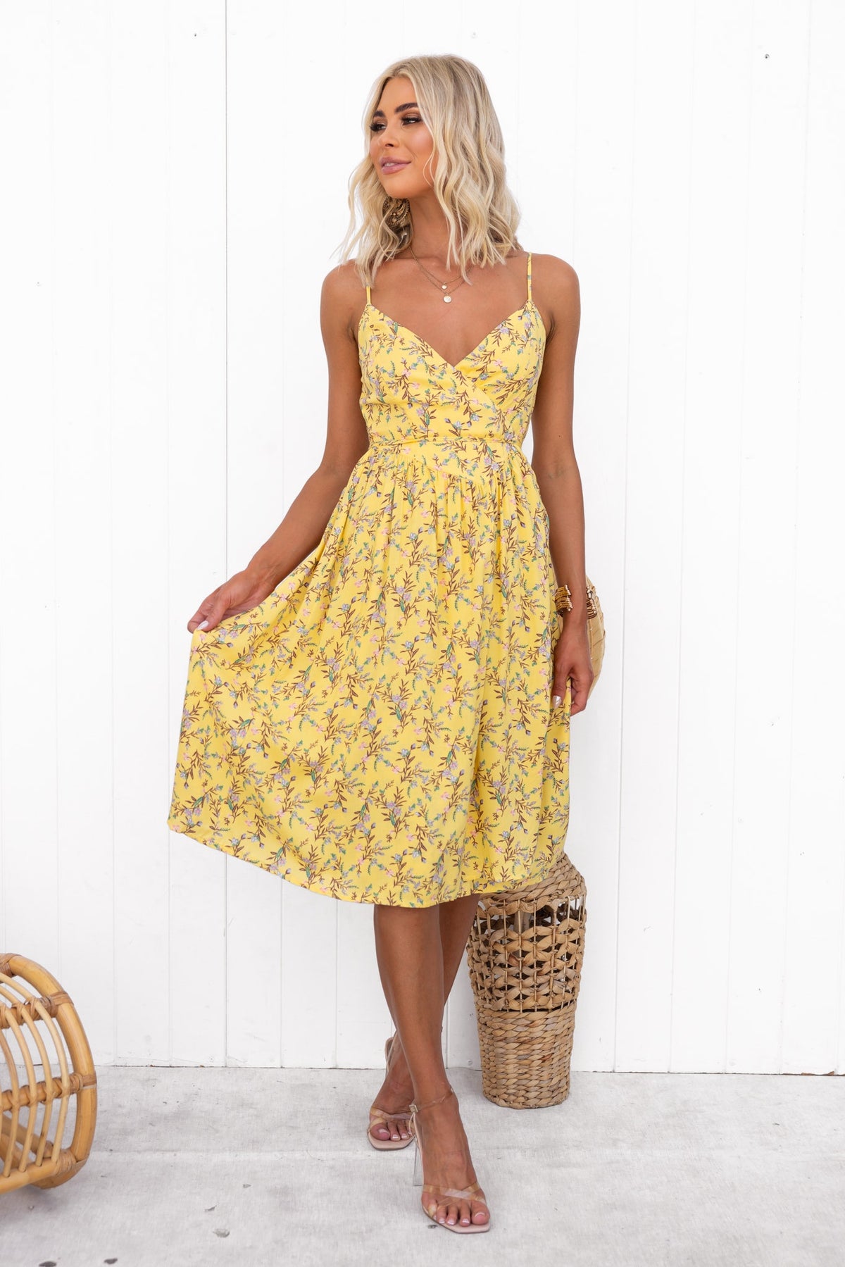 Model wearing a yellow Citrus Wrap Midi Dress with adjustable straps and floral pattern, styled with a bohemian basket.