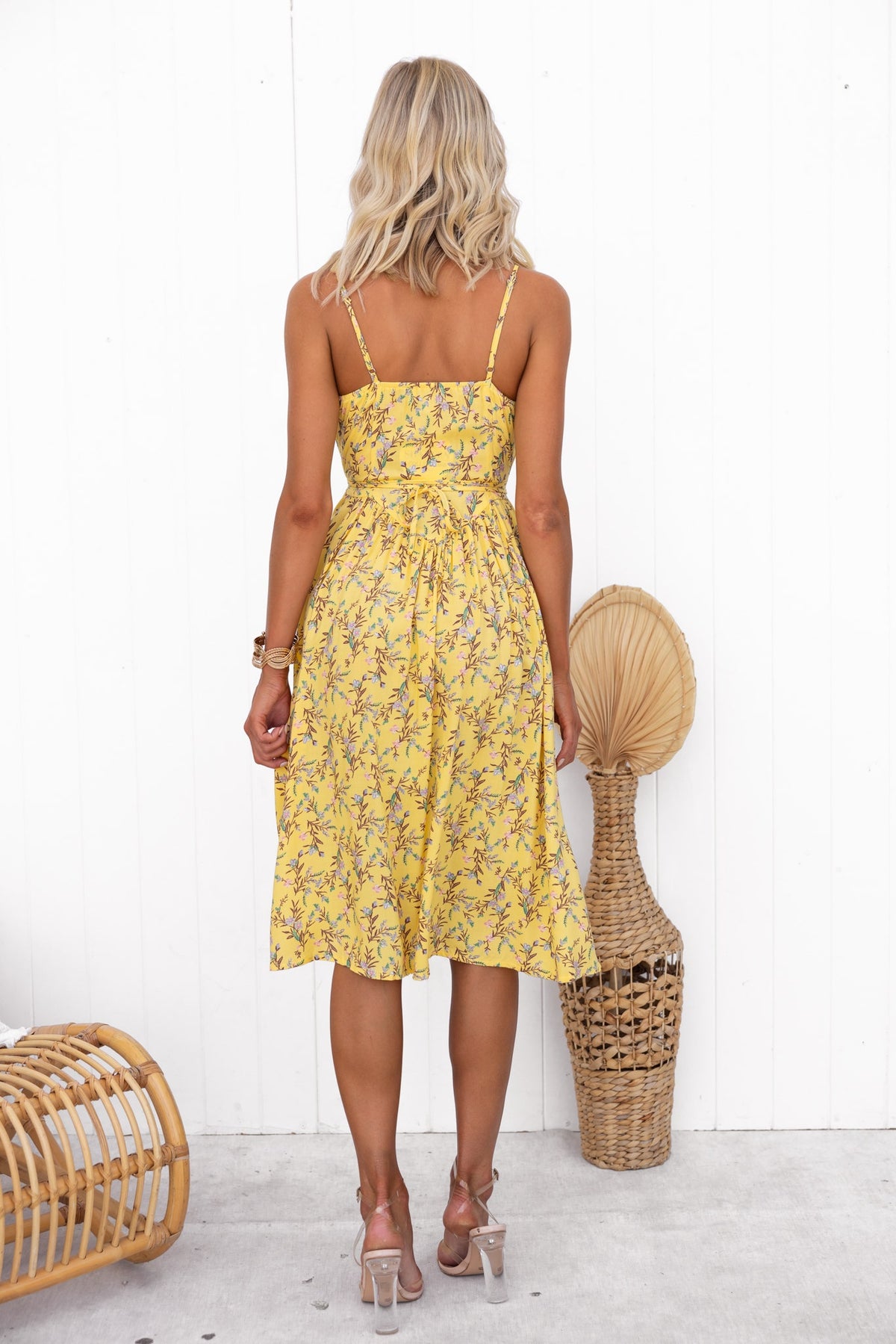 Back view of a woman in a floral Citrus Wrap Midi Dress with adjustable straps and elastic back.