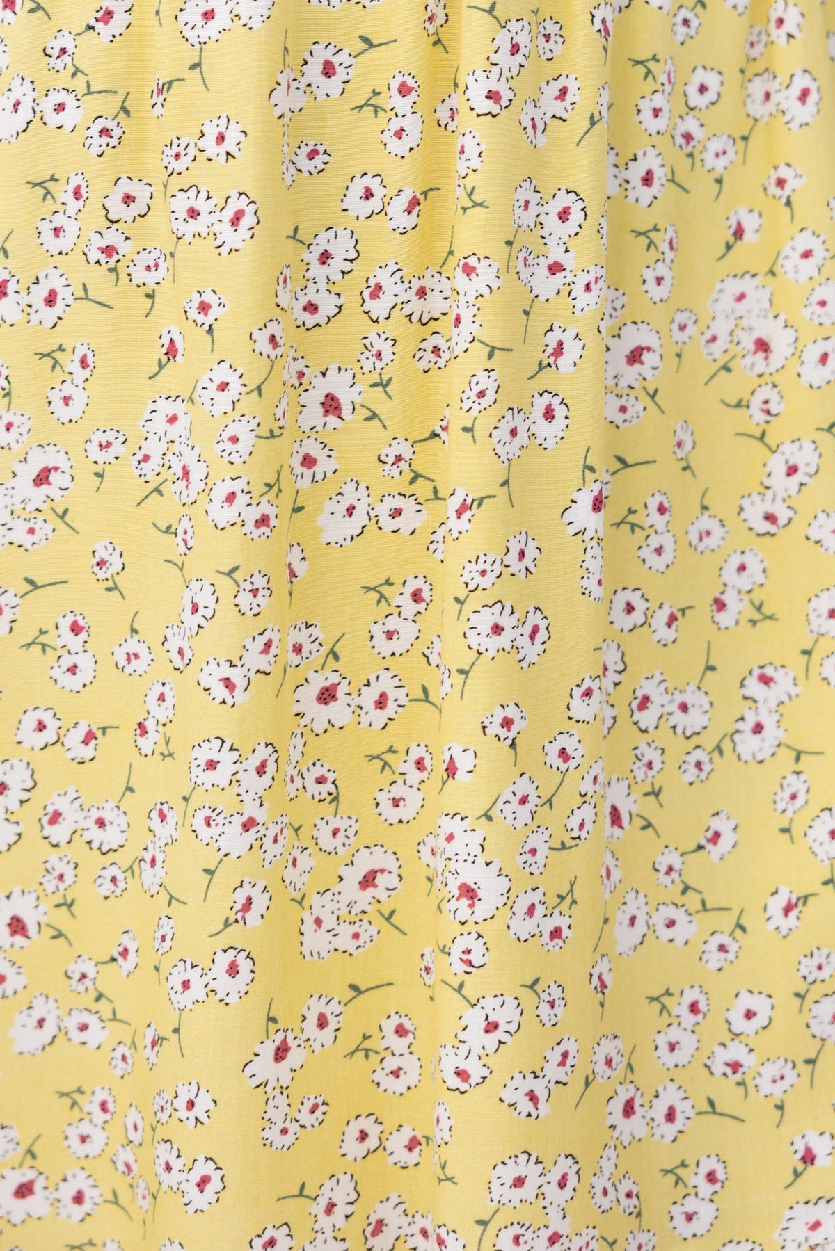 Close-up of floral fabric featuring small white and red flowers on a yellow background for the Mischa Dress.