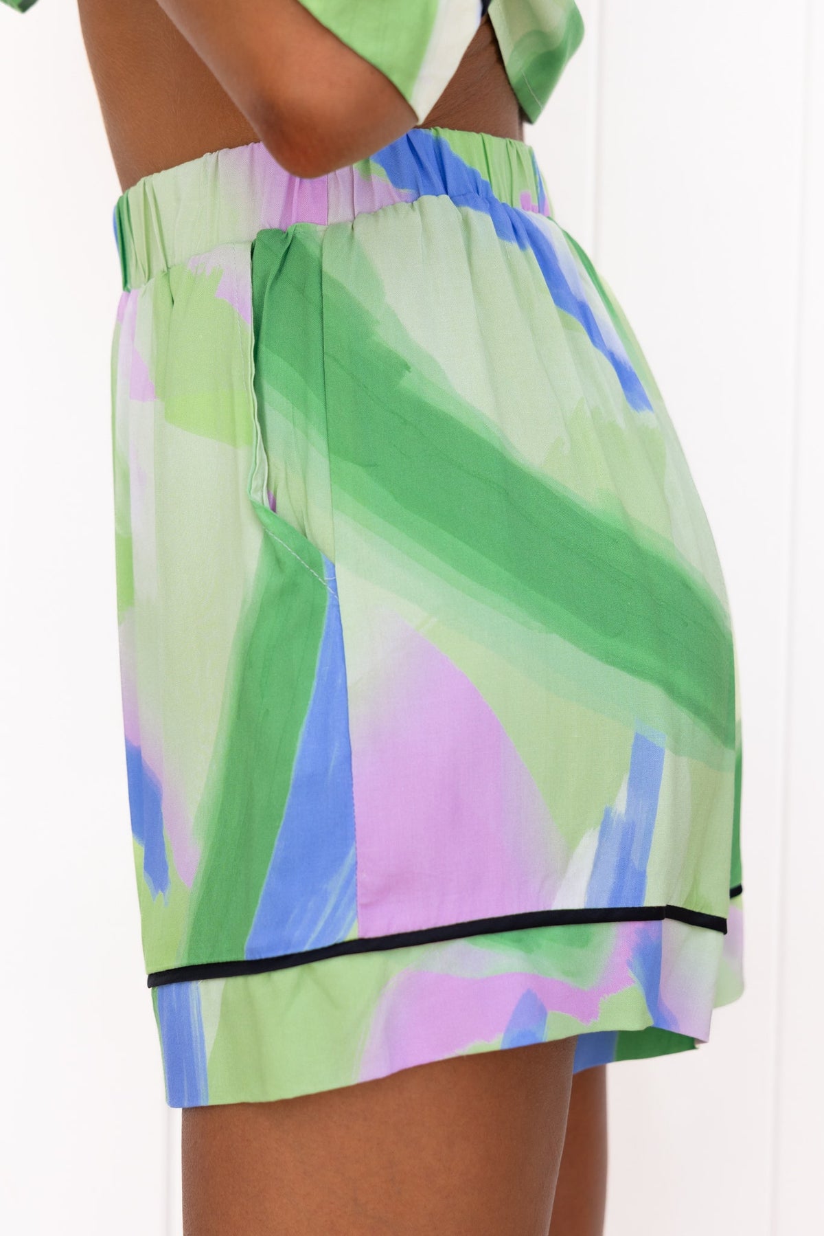 Focus Shorts featuring a mid-high waist fit, elastic waistband, and colorful abstract print in green and purple.