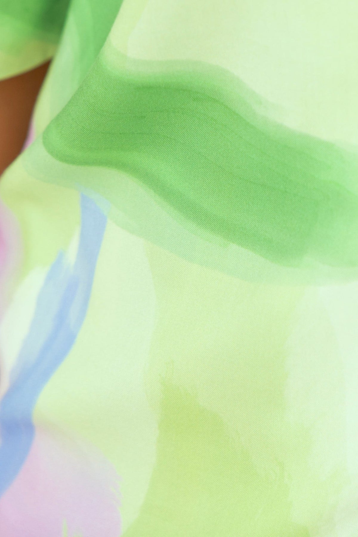Close-up of colorful, lightweight fabric in green and pastel hues, perfect for casual wear.