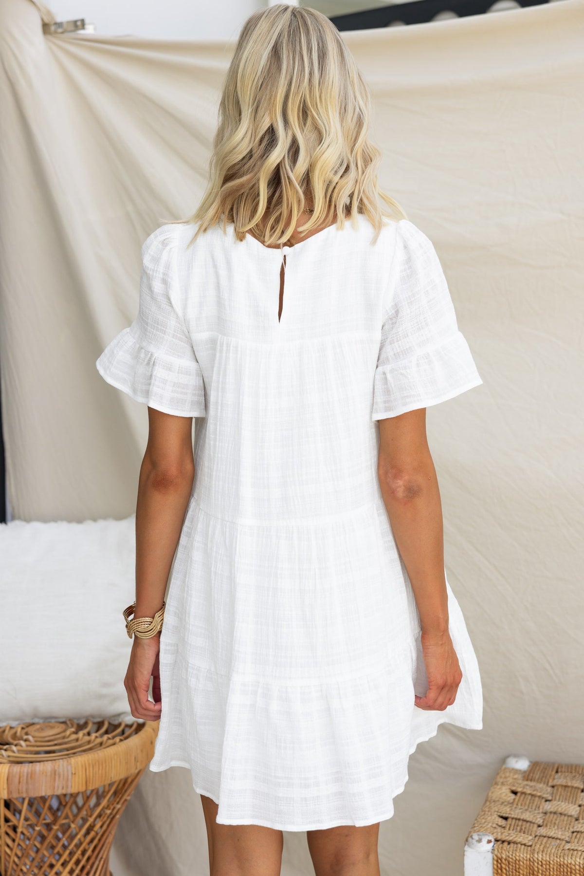 Back view of Parker Dress featuring textured fabric and ruffle sleeves, ideal for relaxed summer outings.