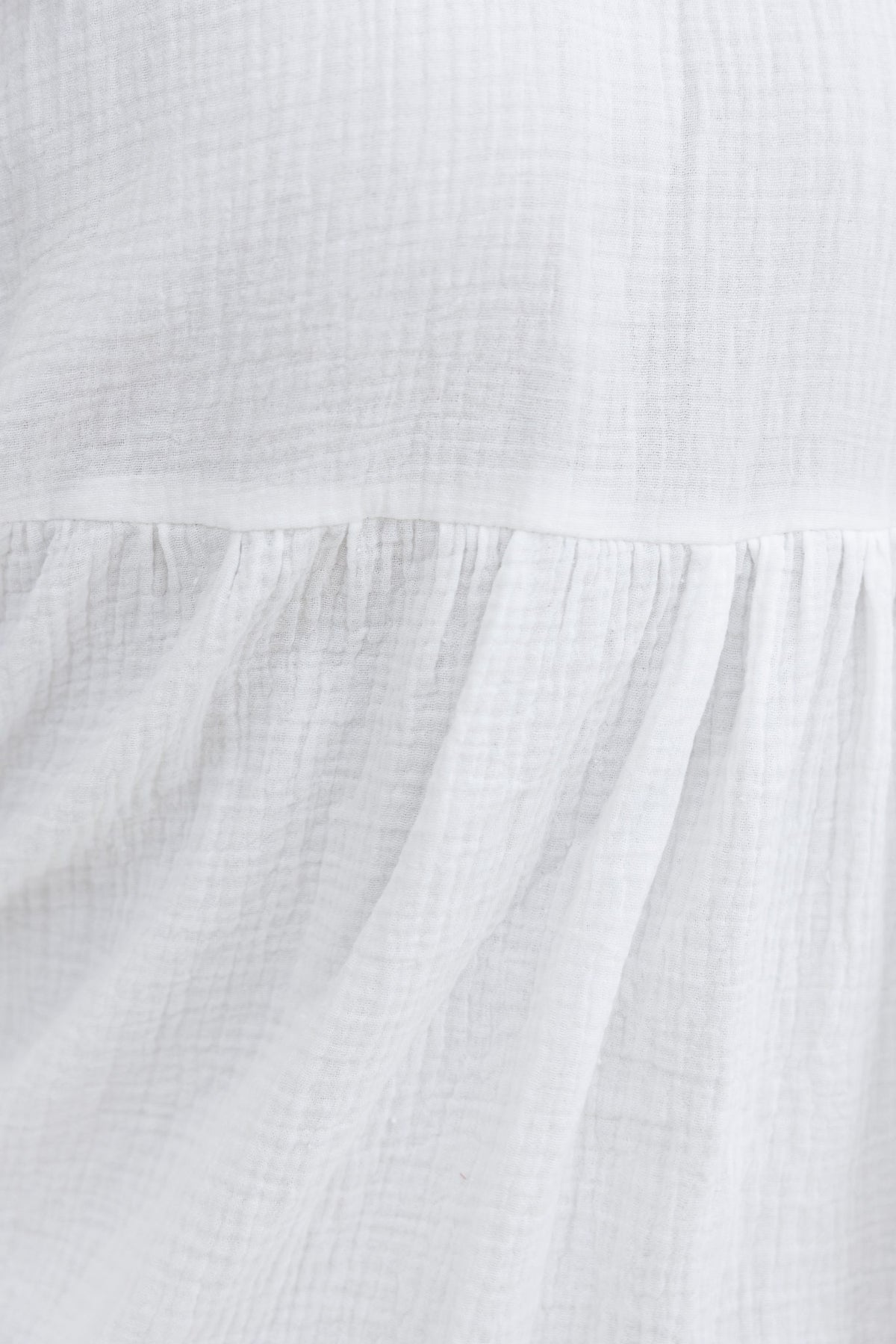Close-up of textured white cotton fabric, showcasing the soft, relaxed fit of the Parker Dress.