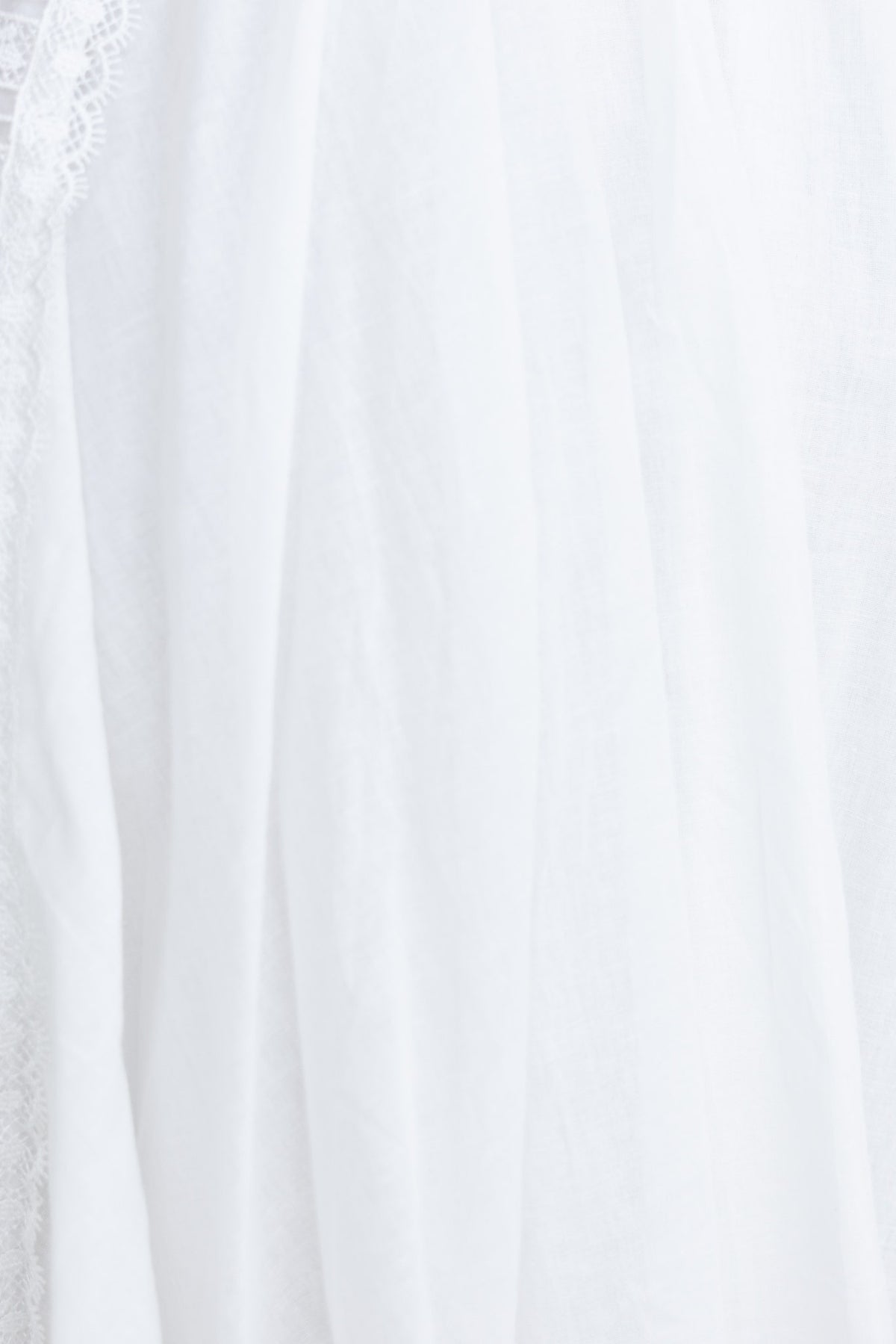 Close-up of the white fabric detailing of the Donissa Dress with lace accents and a soft drape, showcasing a delicate design.
