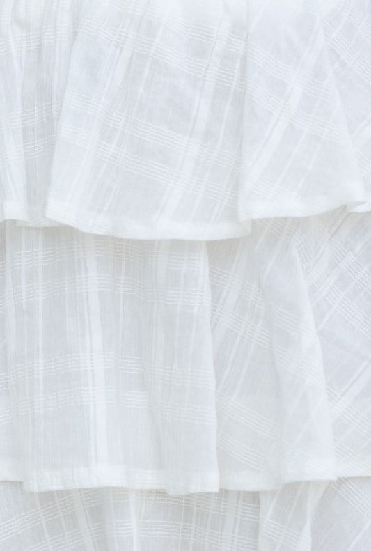 Detail view of the textured white fabric layers of the Madoni Skirt, showcasing its elegant design and lightweight material.