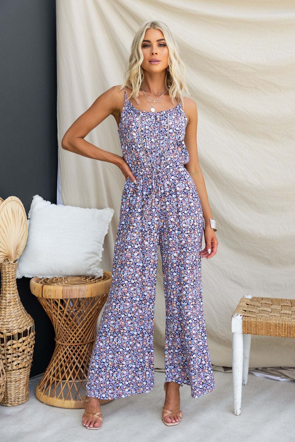 Woman wearing Samia Jumpsuit with adjustable straps and floral pattern, featuring buttons and drawstring waist.