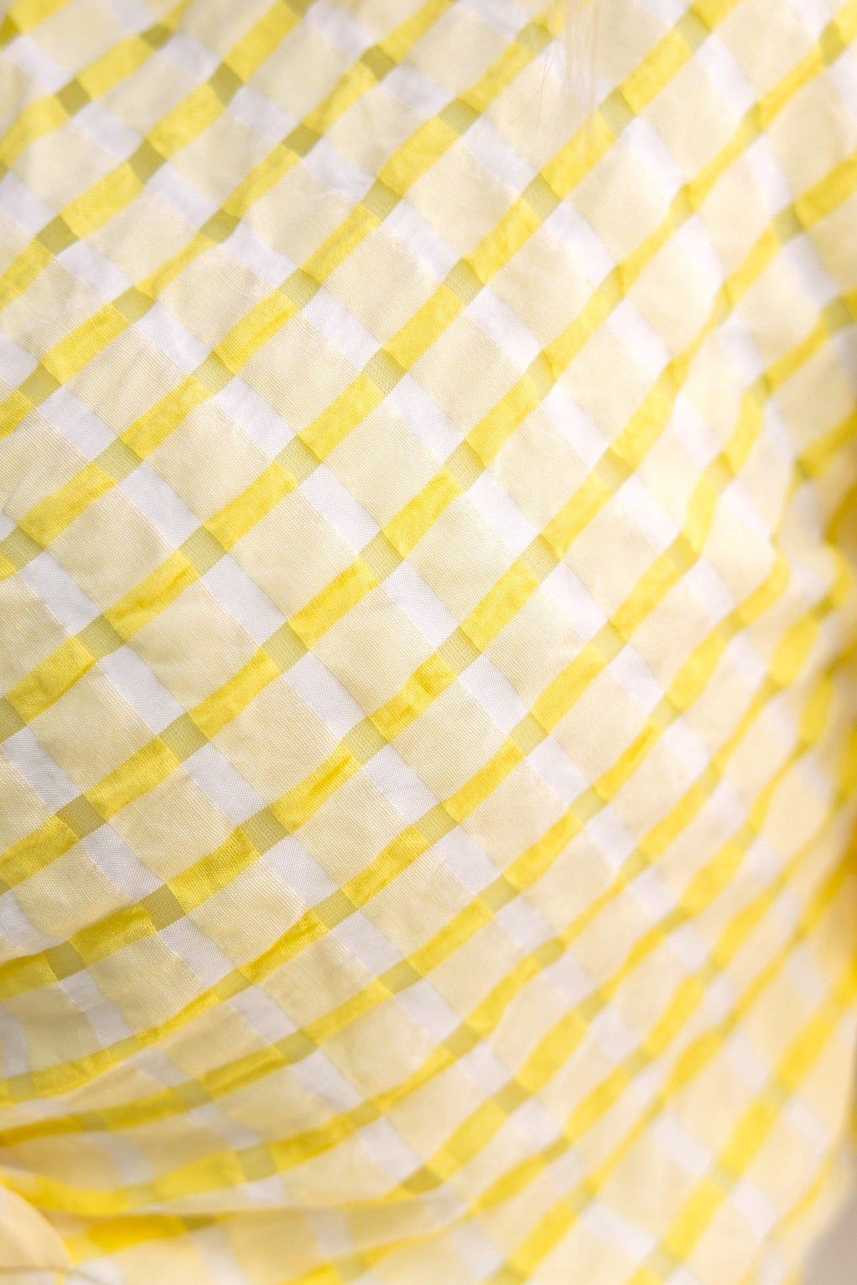 Close-up of a yellow and white checkered fabric pattern, ideal for stylish clothing like dresses.