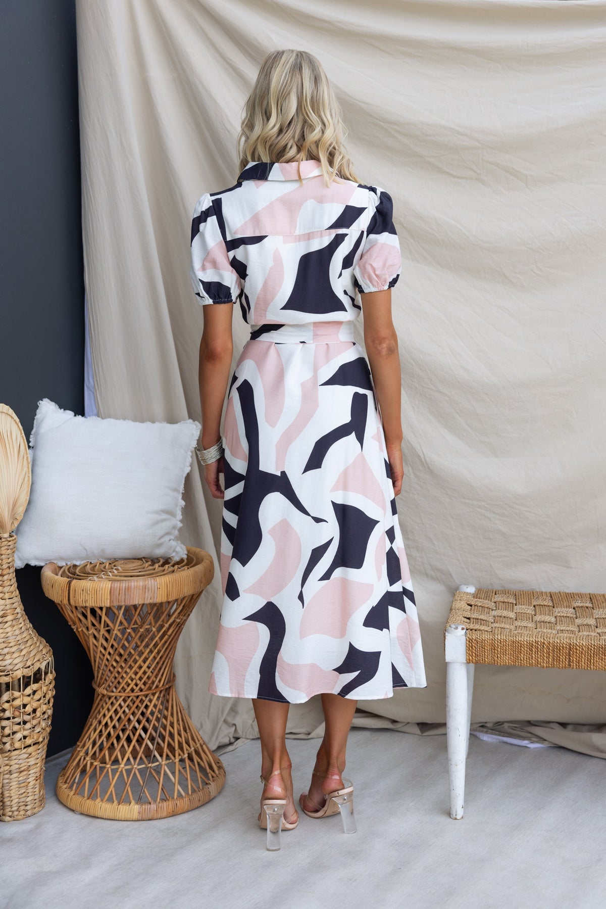 Back view of a woman in a patterned Cappie Midi Dress, featuring a button-up front and puff sleeves.