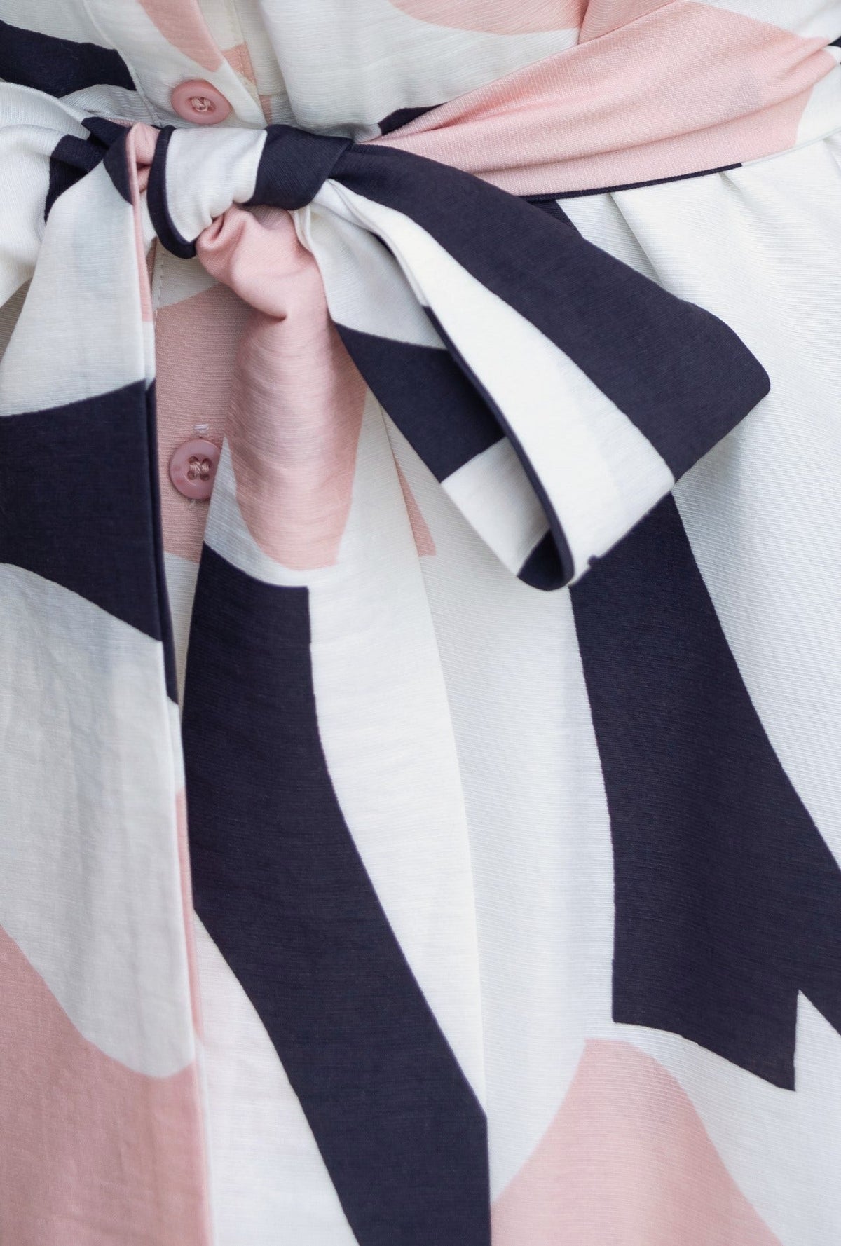 Cappie Midi Dress close-up showcasing button-up front and removable fabric tie detail in elegant patterns.
