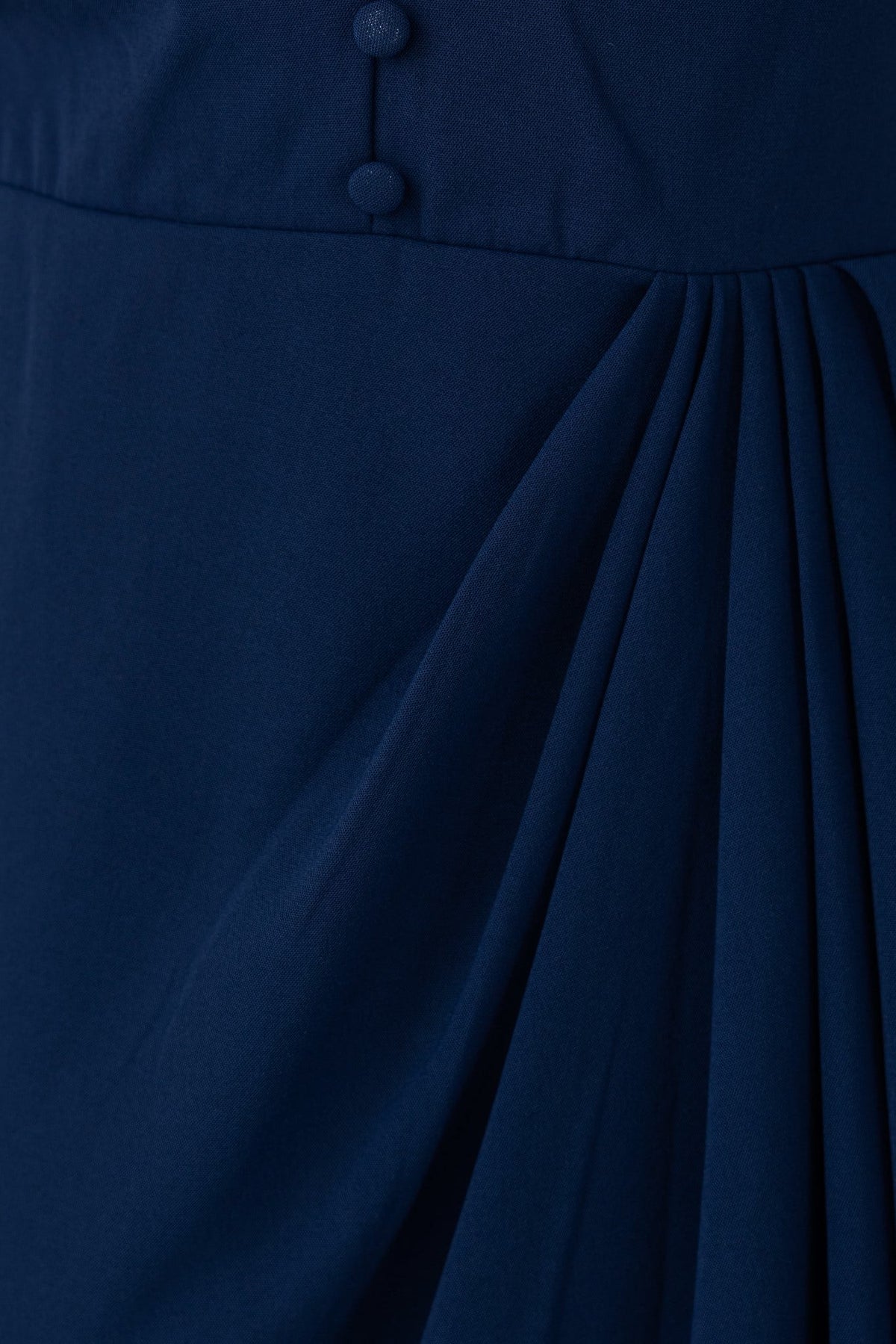 Close-up of navy Hadas Dress featuring faux buttons and elegant pleats.