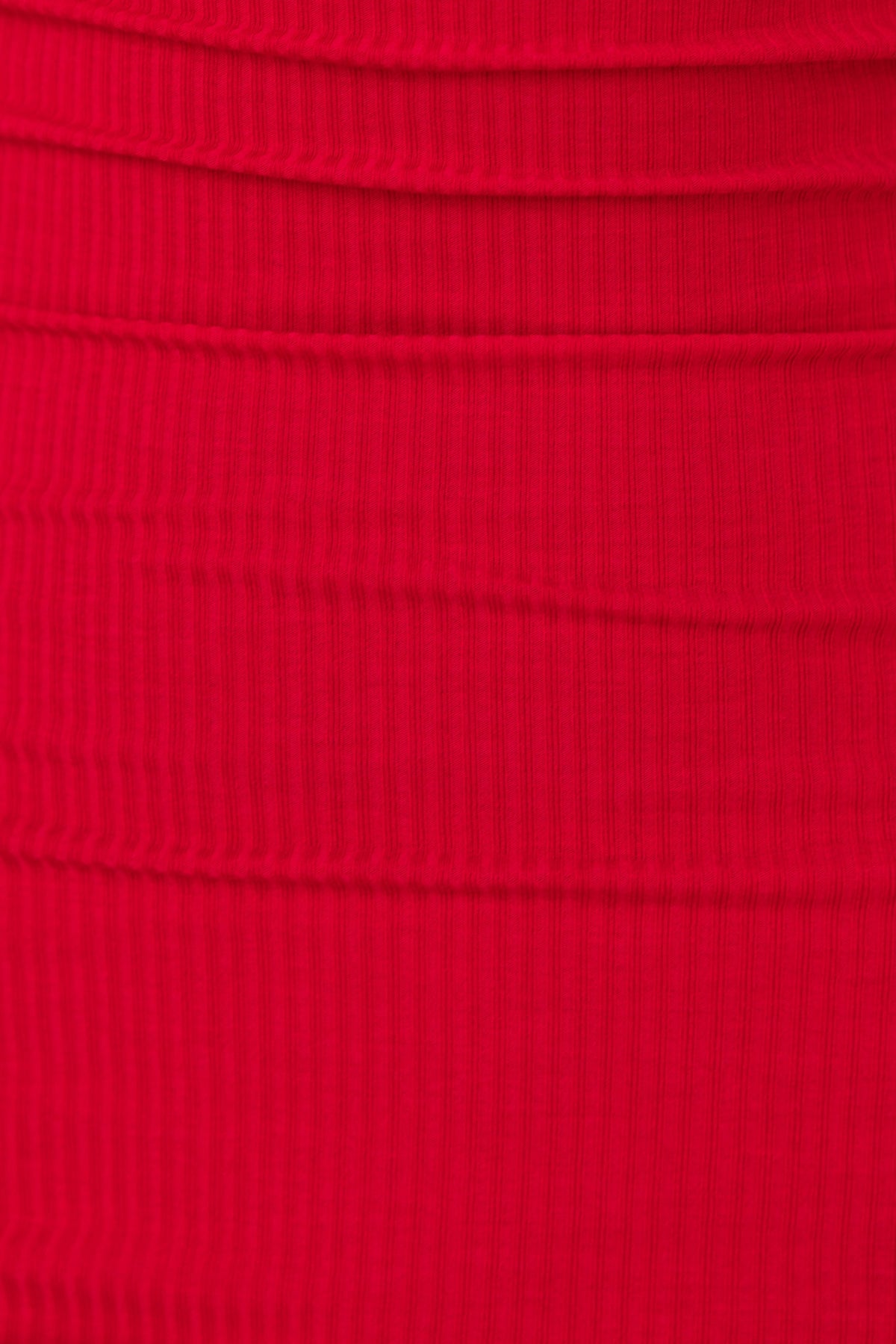 Close-up of the ribbed texture in a vibrant red fabric, showcasing the material of the Betzi Dress.