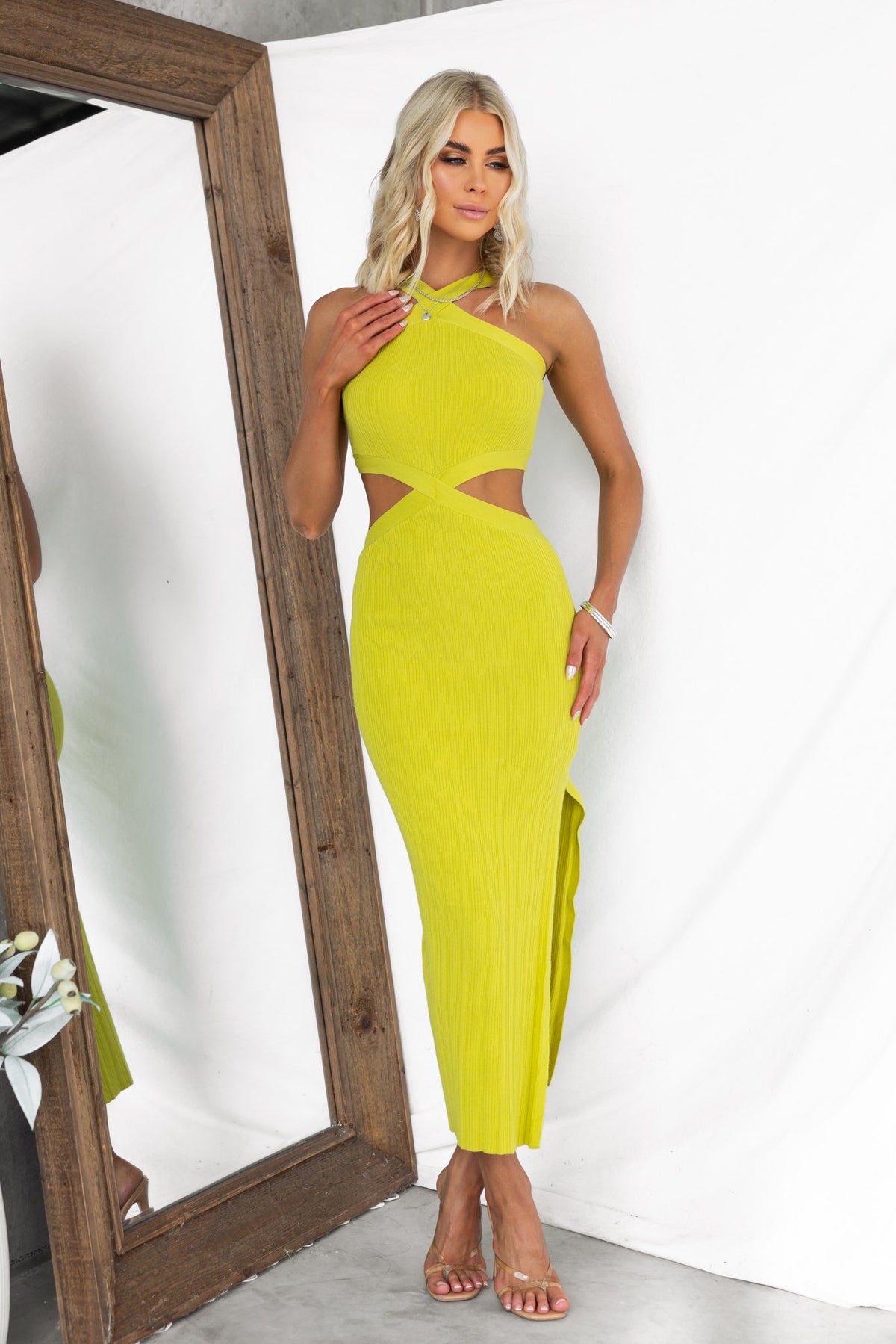 Oura Midi Dress in vibrant lime green with cross-over neckline, cut-out at waist, and side split, modeled in a stylish setting.
