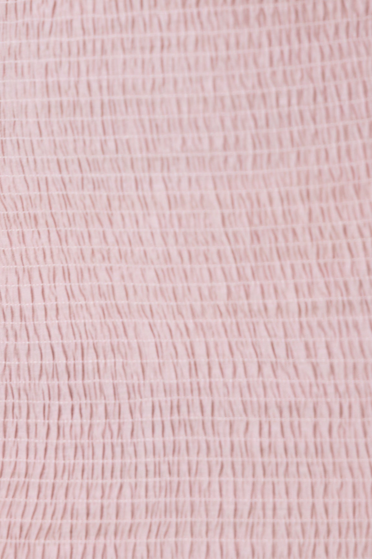 Close-up of soft, textured pink fabric showcasing a delicate crinkled design for stylish apparel use.