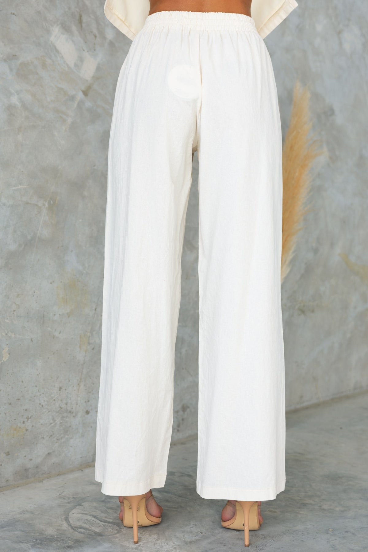 Back view of Vesper Pants with mid-high waist, elastic waistband, and wide-leg fit in white, perfect for summer styling.