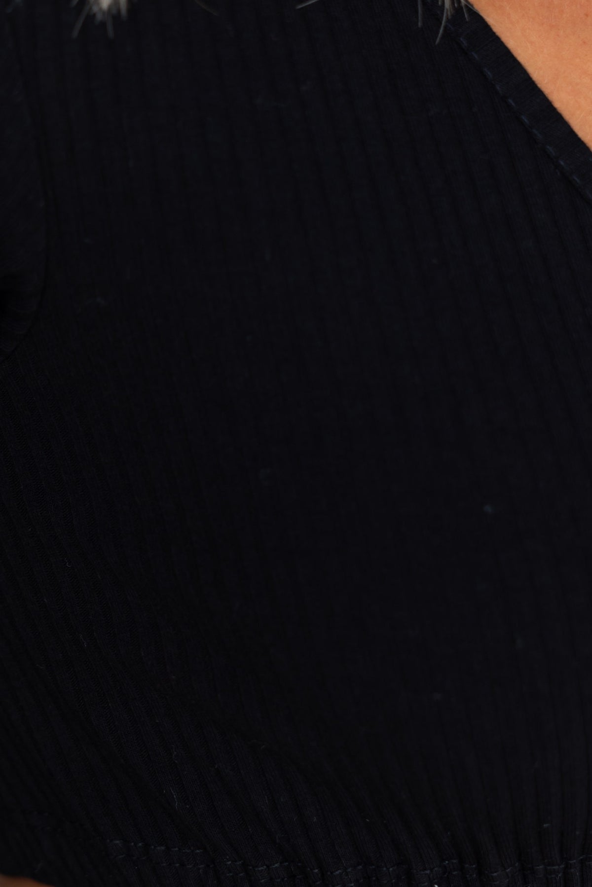 Close-up of Albie Top in black with V-neckline and ribbed material, showcasing adjustable tie and elastic hem.