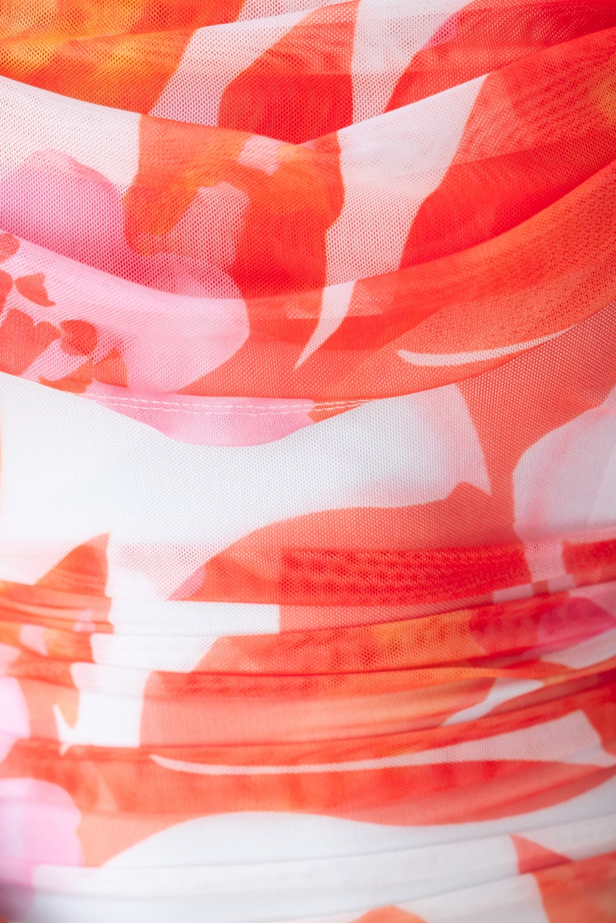 Close-up of floral patterned fabric in shades of orange and white, showcasing the draping and ruching details of the Carlie Maxi Dress.