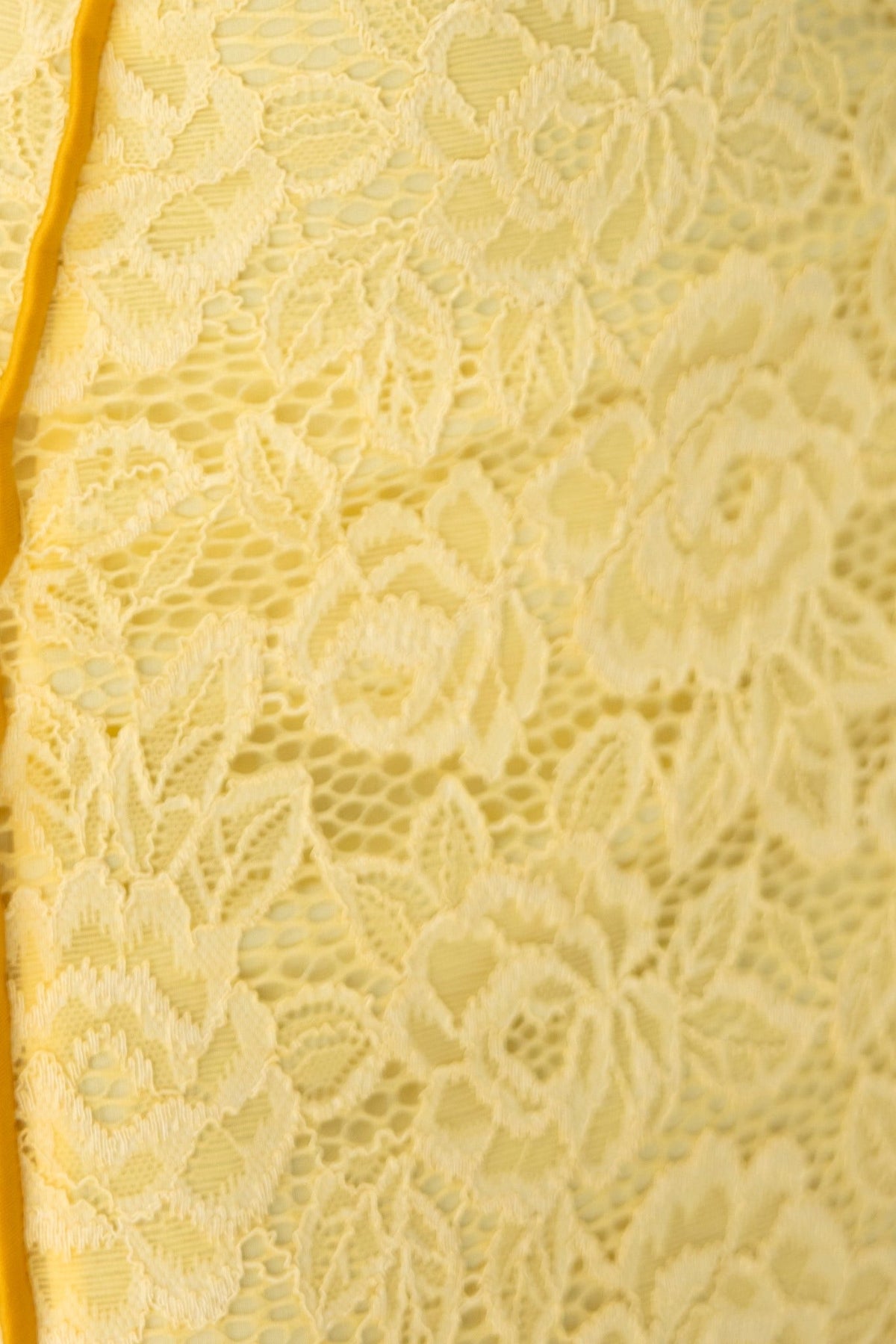 Close-up of delicate yellow lace fabric with floral patterns, showcasing texture for the Charisma Maxi Dress.