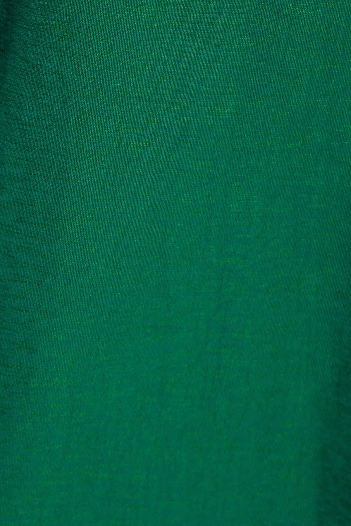 Textured green fabric close-up, showcasing the rich hue and weave of the material used in apparel.