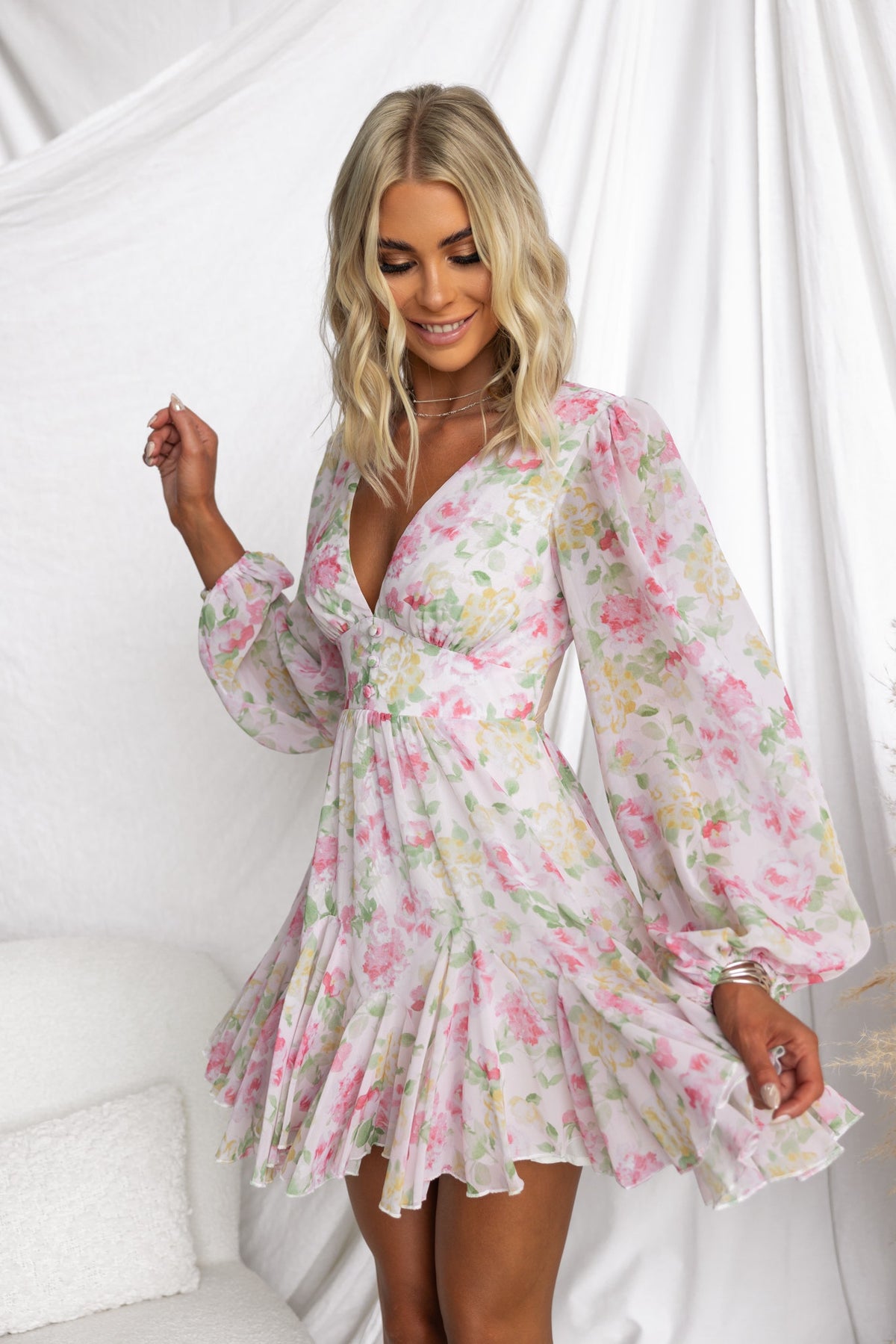 Model wearing a floral Kersty dress with a V-neckline, puff sleeves, and flared skirt, captured in a bright setting.