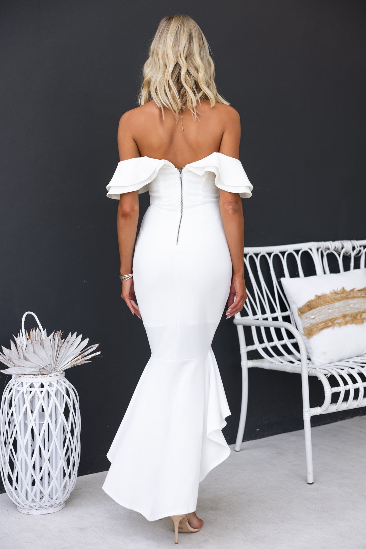 Model wearing a Giavanna maxi dress in white, showcasing off-shoulder neckline and high-low hem.