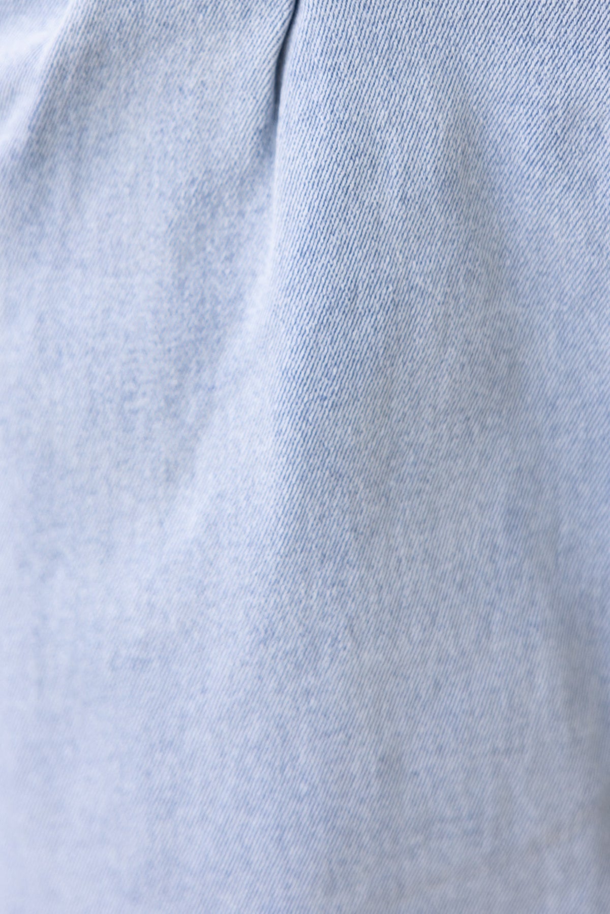 Close-up of the fabric texture of an Emera Denim Midi Skirt, showcasing a soft light blue denim.