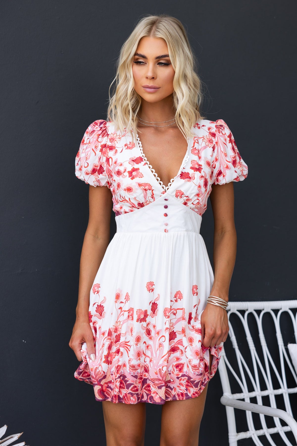 Model wearing the Lenika Dress, a floral v-neckline dress with puff sleeves and a button-up front, perfect for summer.