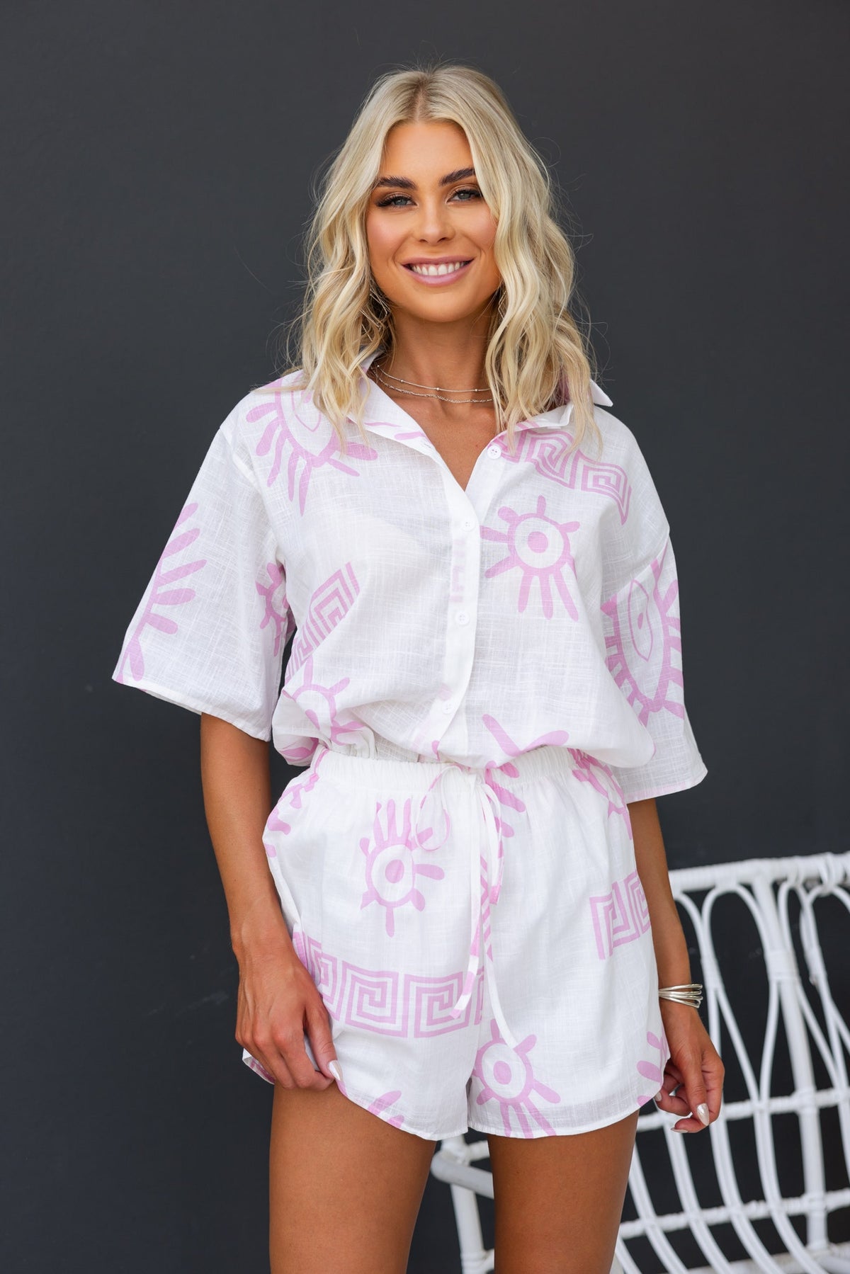 Model wearing the Tamba Set featuring a pink patterned button-up shirt and matching shorts with an elastic waistband.
