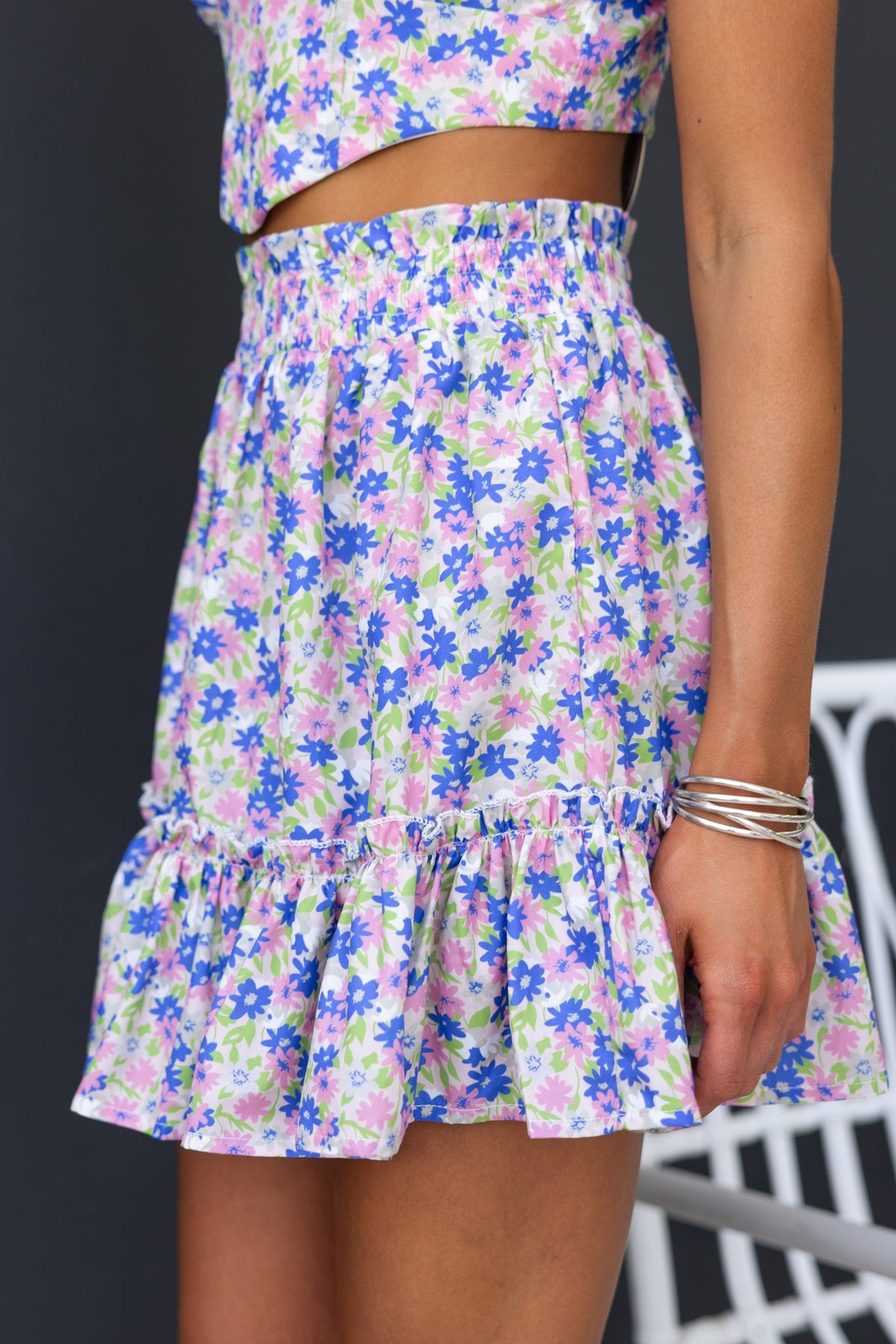 Floral Syana skirt with mid-high waist fit and ruffled hem, showcasing vibrant colors and elastic waistband.