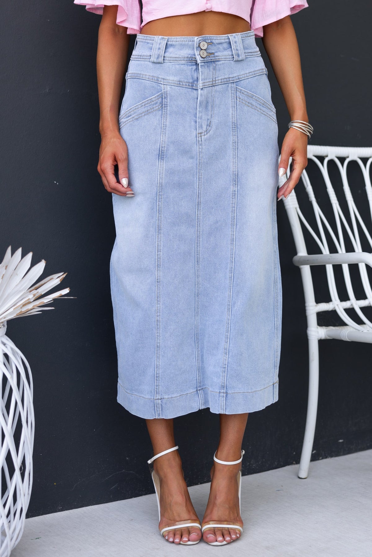 Azra Denim Midi Skirt featuring a mid-high waist, front pockets, and a casual chic look styled with heels.