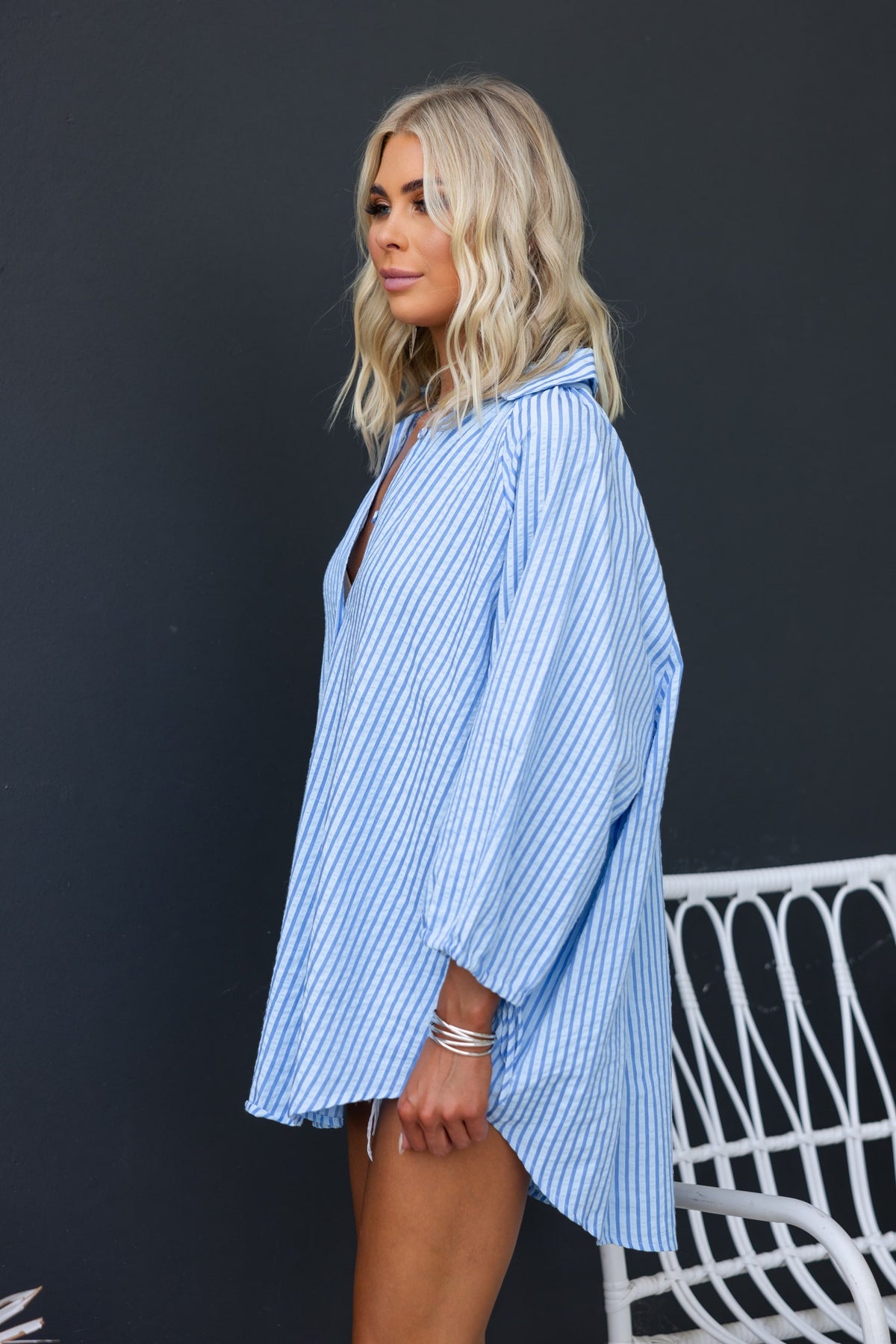 Side view of a woman wearing a blue and white striped oversized Sorbet Shirt with a collar and tie detail at sleeves.