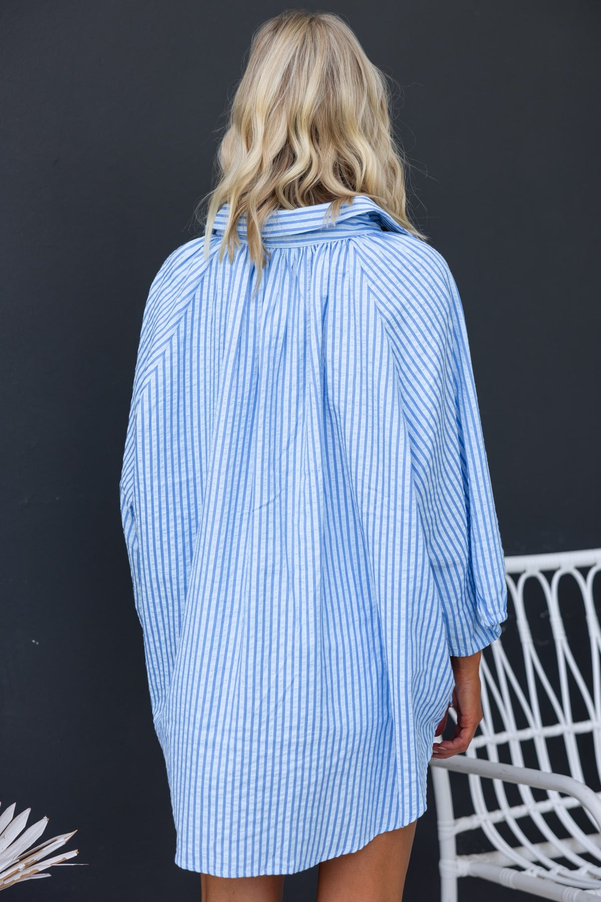 Back view of a woman in a blue and white striped oversized Sorbet Shirt with button-up collar and tie sleeves.