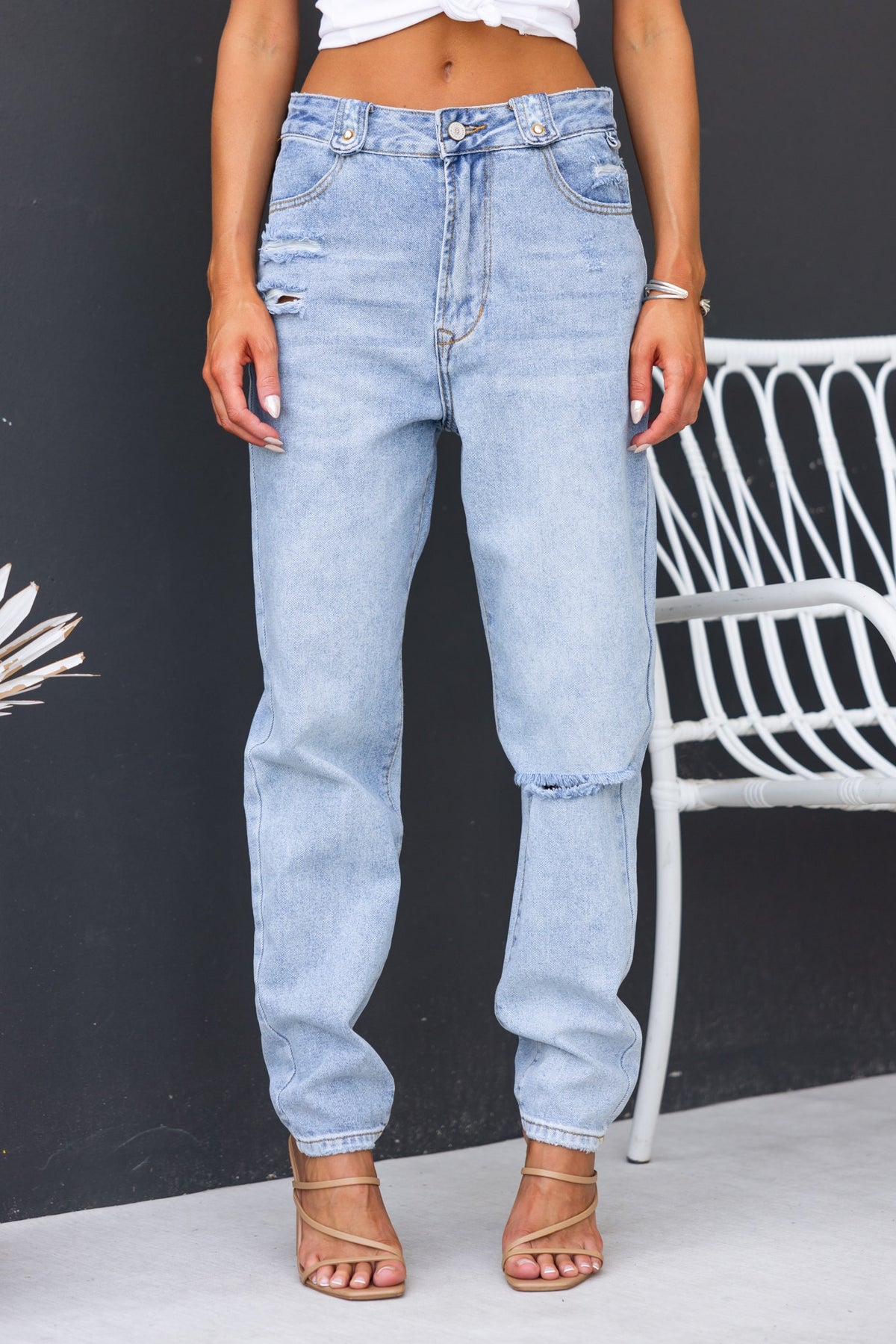 Model wearing Kaylie Jeans, mid-high waist denim with distressed details and a relaxed boyfriend fit.
