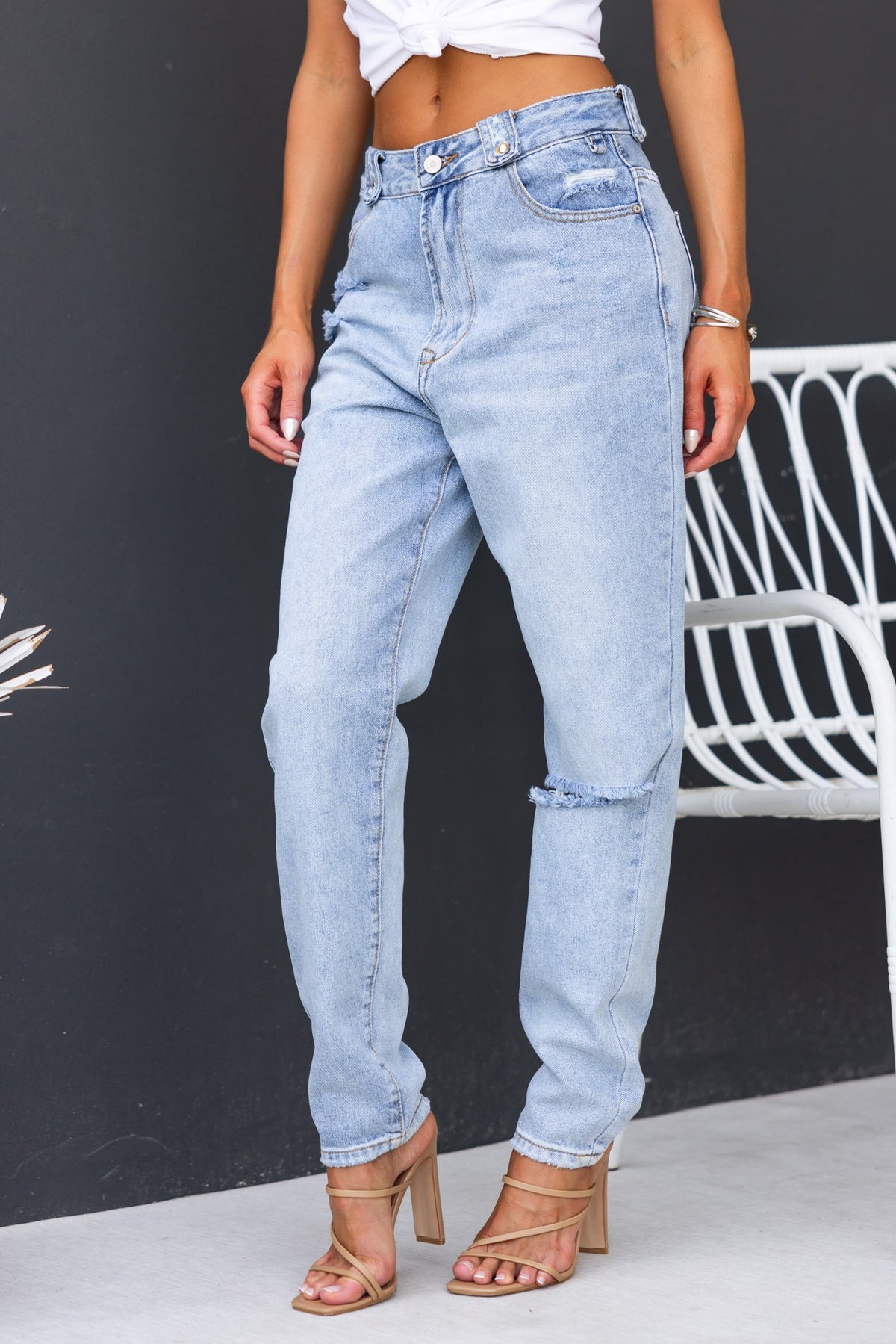 Model wearing Kaylie Jeans, mid-high waist denim with distressed detail and boyfriend fit in light wash.