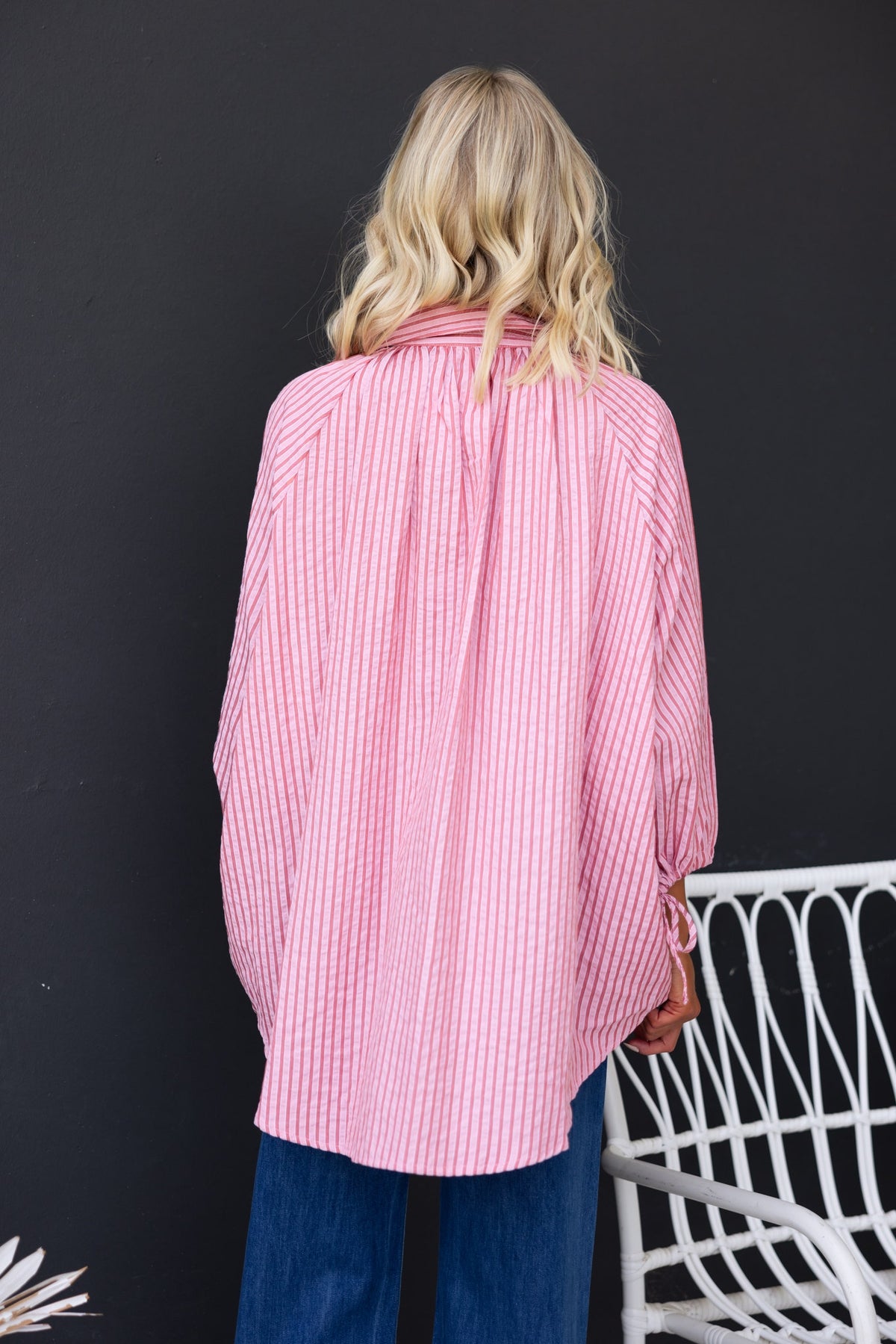 Back view of a woman wearing a pink striped oversized Sorbet Shirt with a shirt collar and tie detail at sleeves.