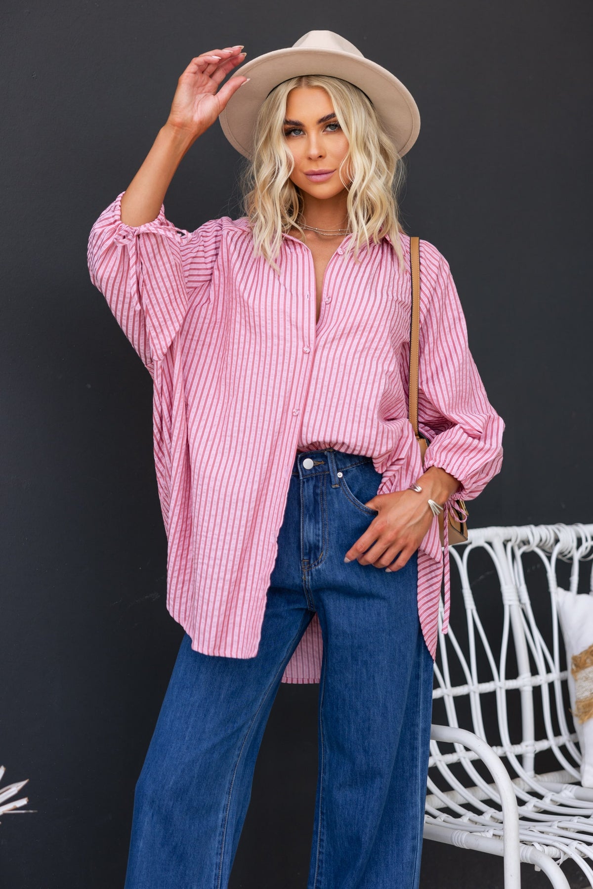 Model wearing oversized pink striped Sorbet Shirt with button-up front and tie details, paired with blue jeans and a hat.