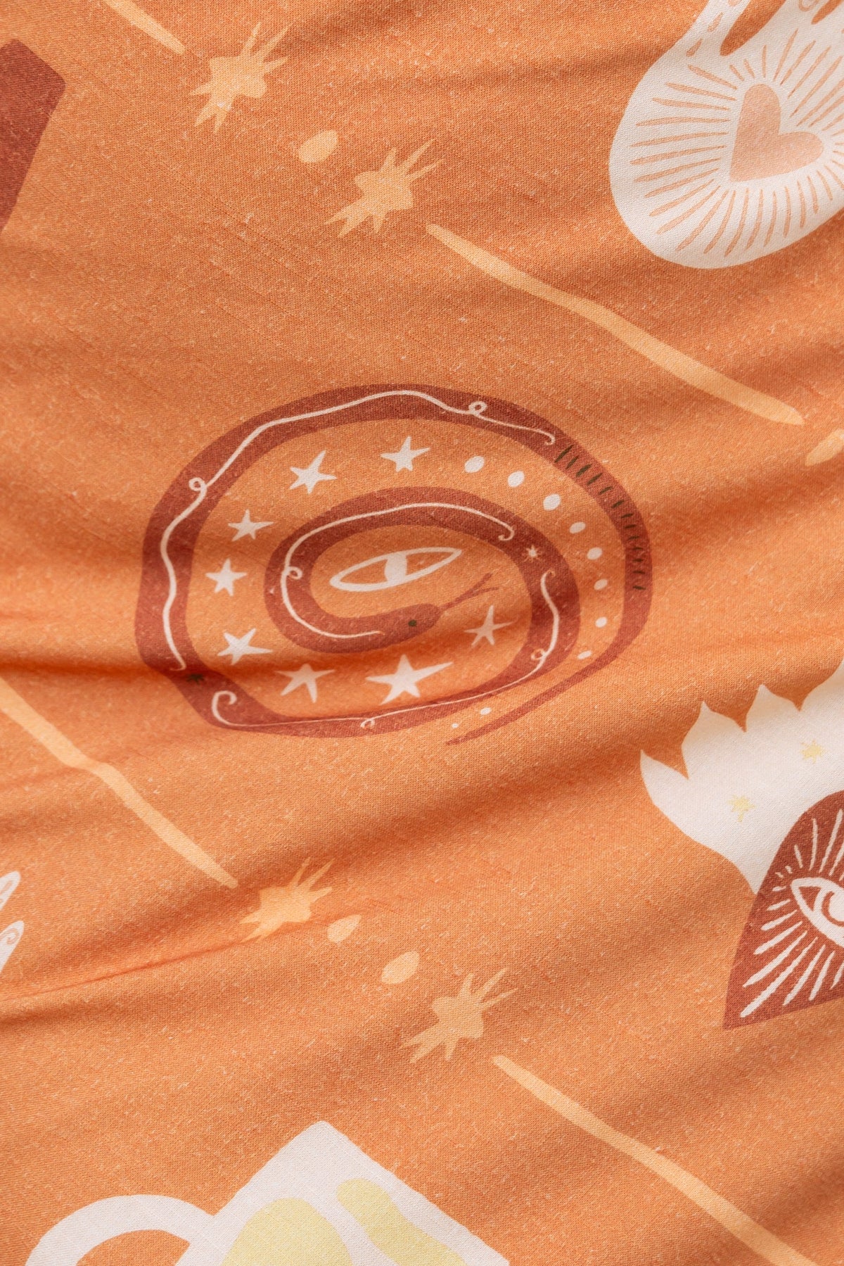Close-up of orange fabric featuring unique spiral and star patterns, perfect for a stylish maxi dress.