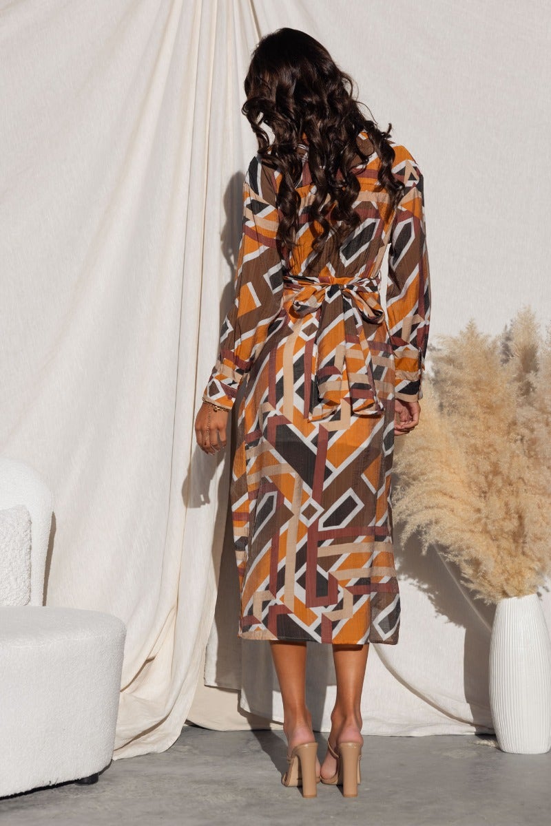 Back view of a model in a multi-colour Sommer midi dress with a collar and tie detail, showcasing an asymmetrical hemline.