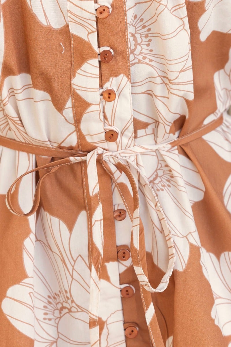 Detail of Mellow Dress featuring floral print, round neckline, button-up front and removable fabric tie.